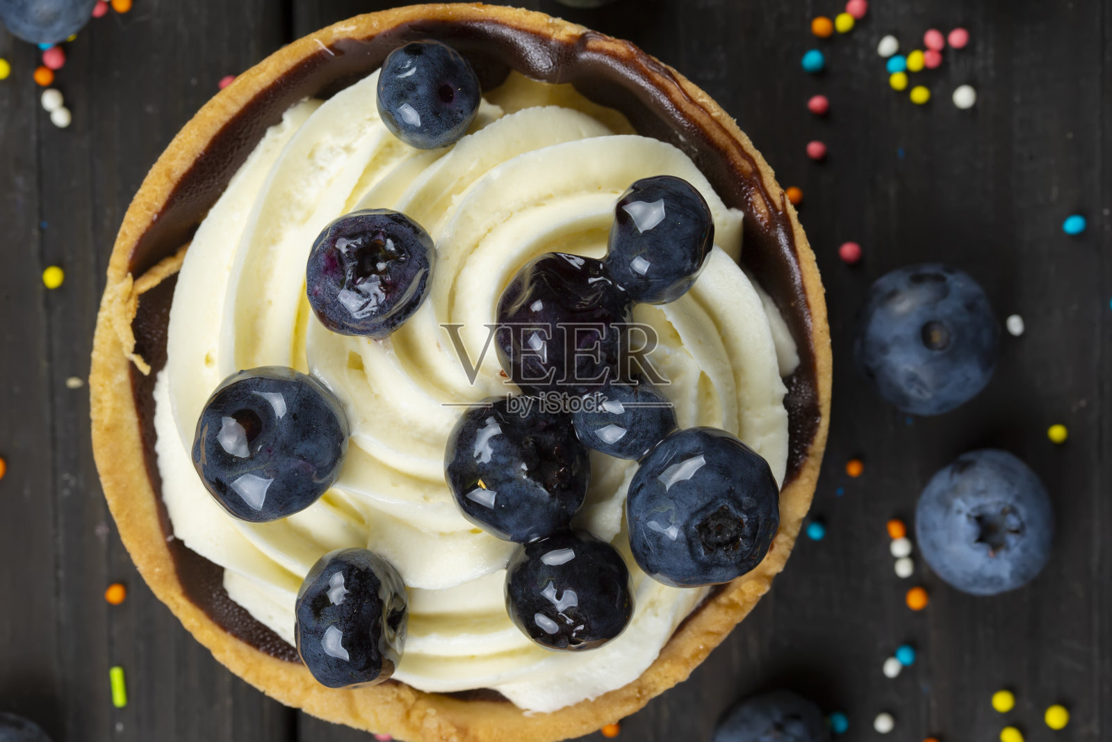 不错的食物。黑色背景上有奶油和浆果的小蛋糕。照片摄影图片