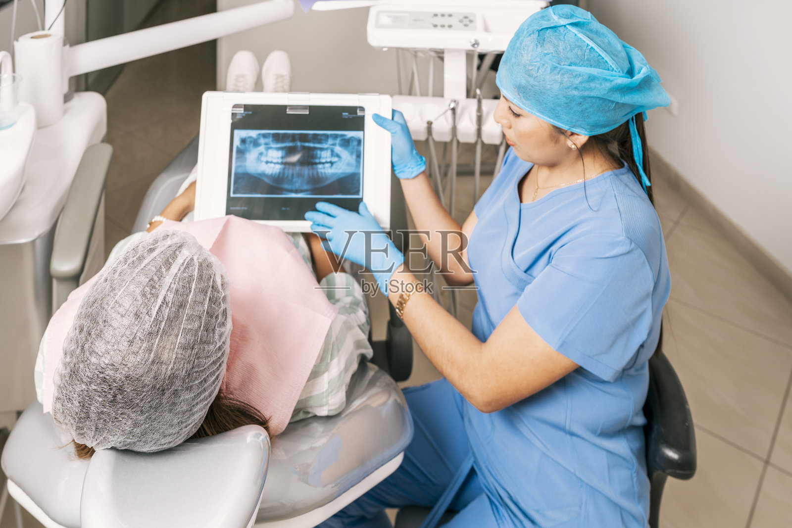 牙科诊所里，牙医一边给病人看x光片，一边和病人交谈照片摄影图片