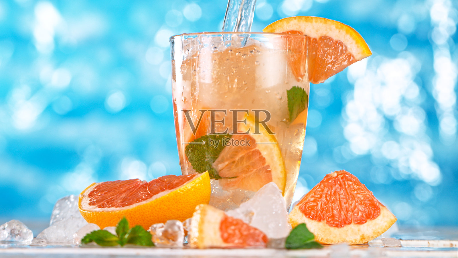 冰块落入柑橘柠檬杯与海面背景。照片摄影图片