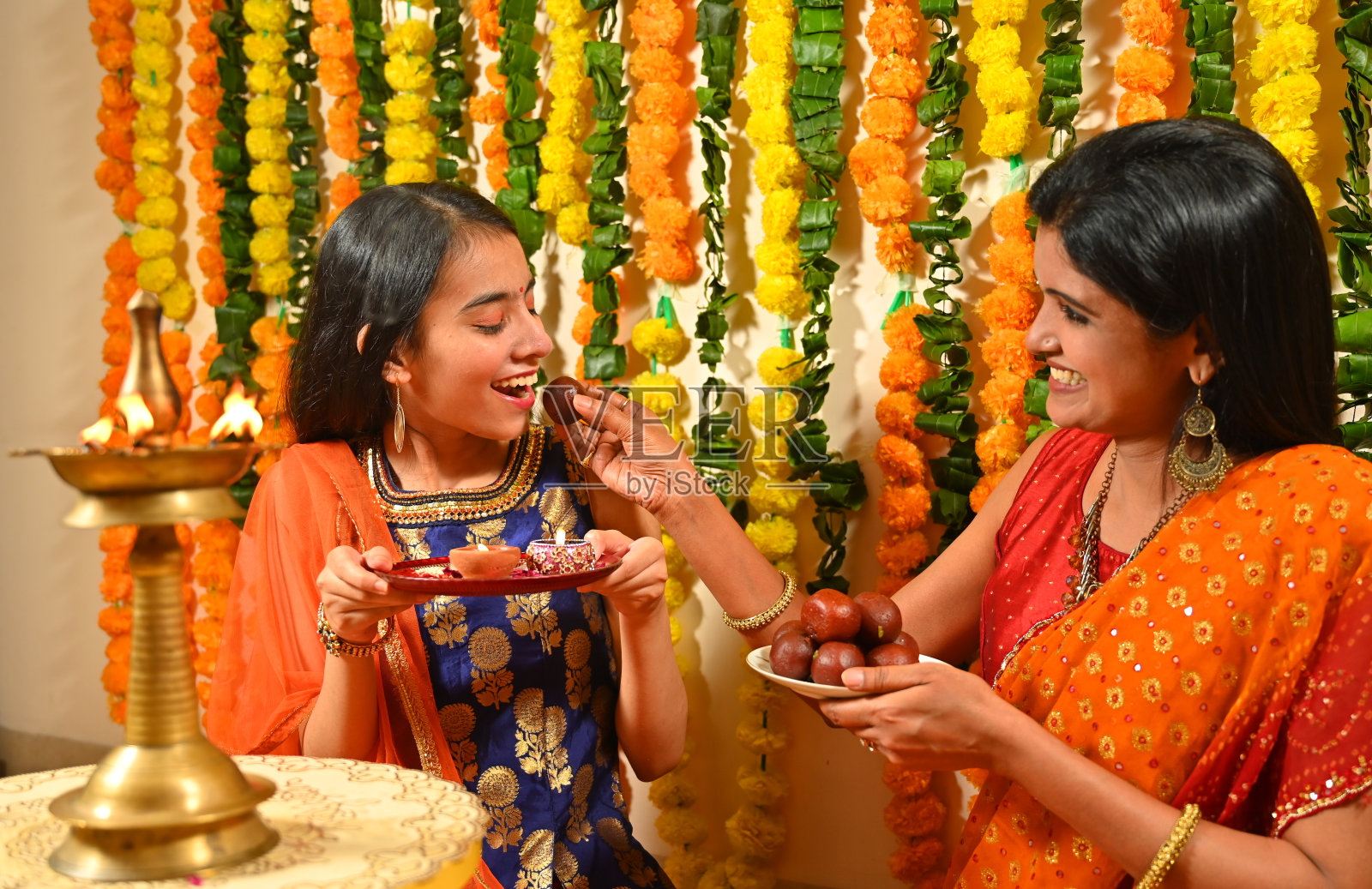 母亲和女儿穿着传统服装，点燃蜡烛照片摄影图片