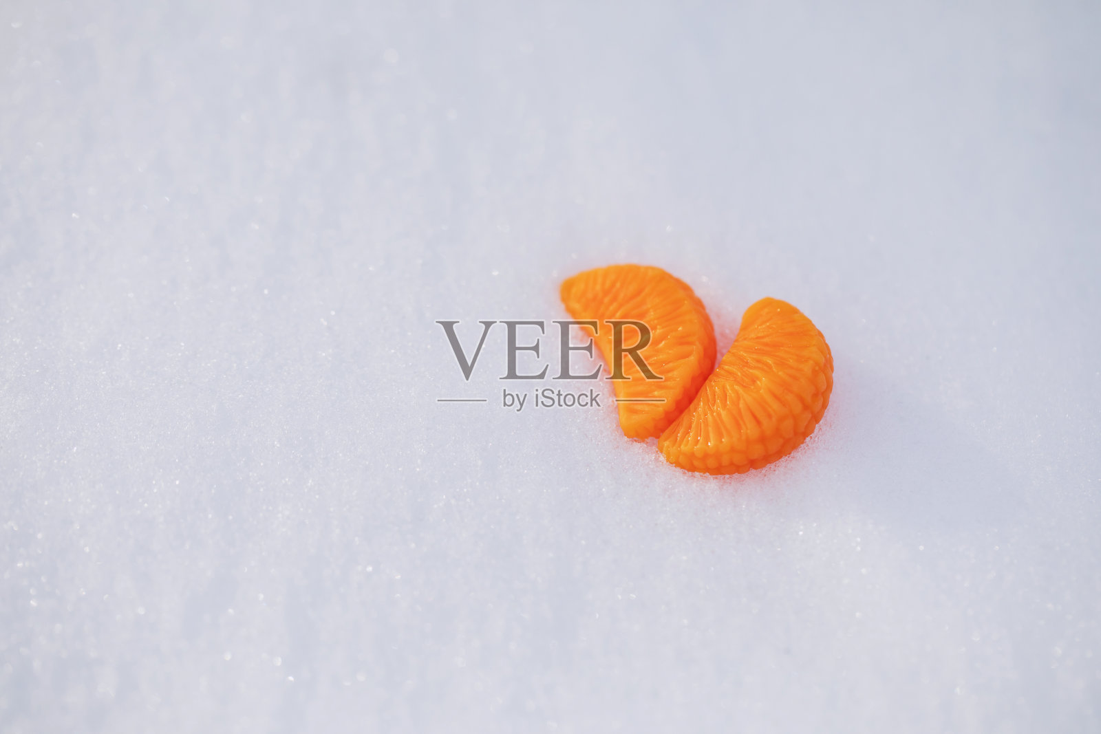 用粘土做成的小桔片躺在洁白的雪地上。新年的光电话与文字的地方为设计照片摄影图片
