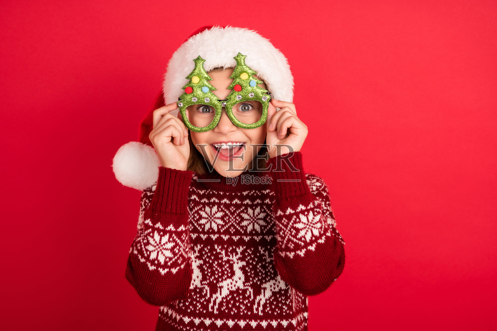 迷人开朗的女孩的肖像触摸戴节日的眼镜圣诞前夕孤立在明亮的红色背景照片摄影图片