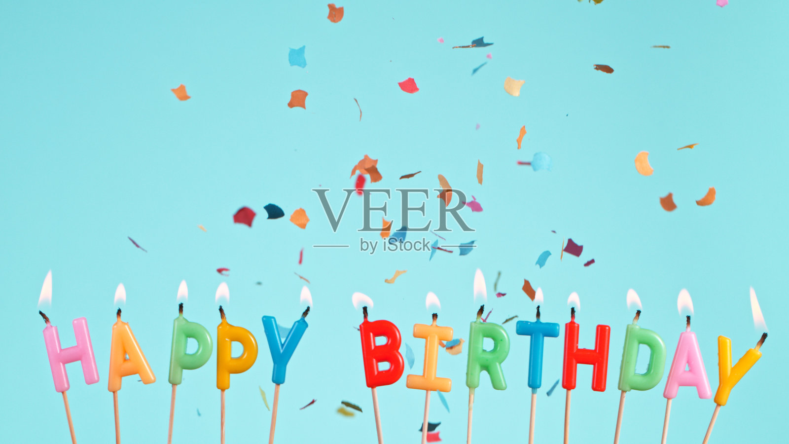 彩色的纸屑飘落，蓝色的背景上写着生日快乐的题词照片摄影图片