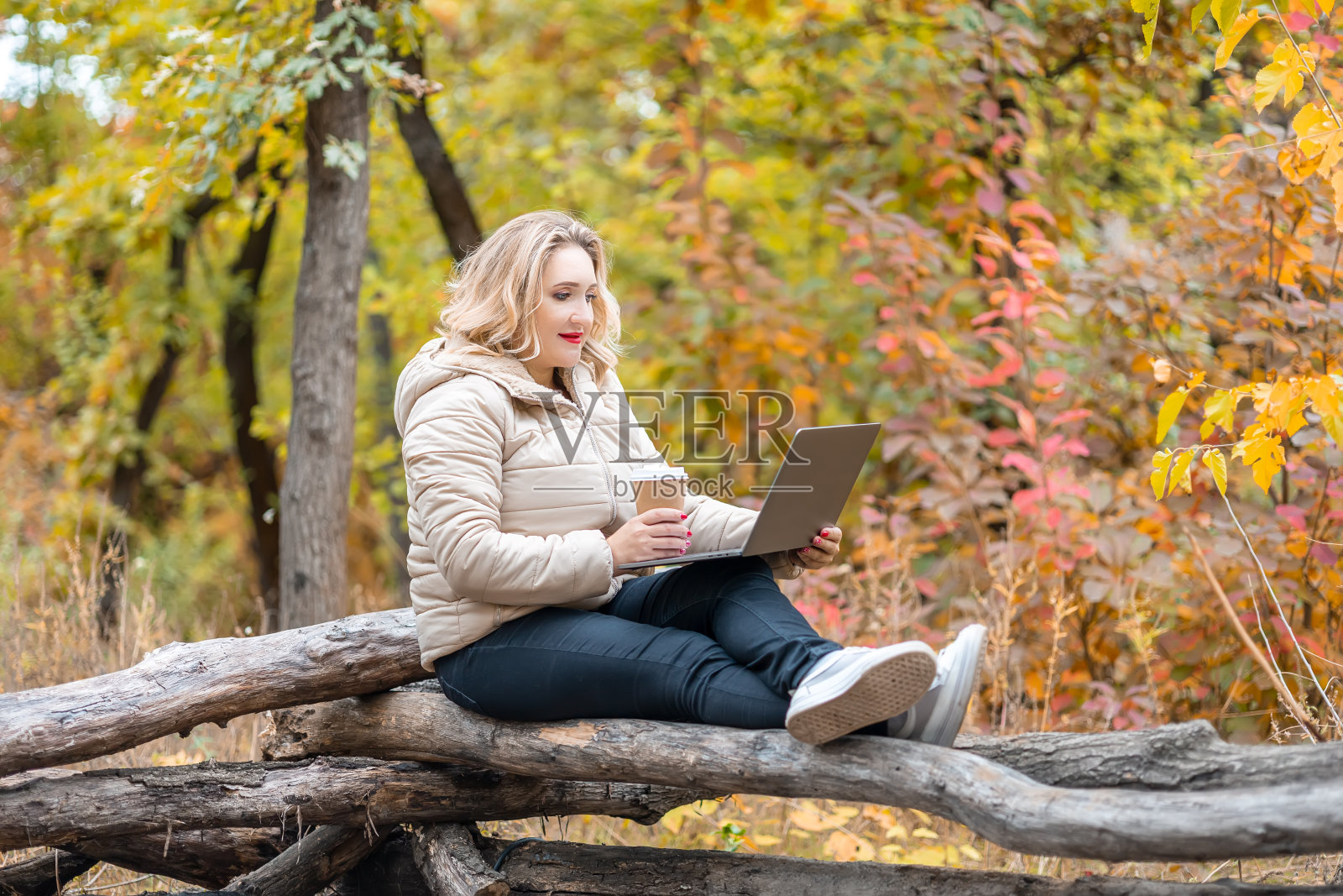 秋天里，一个手里拿着笔记本电脑的女人照片摄影图片