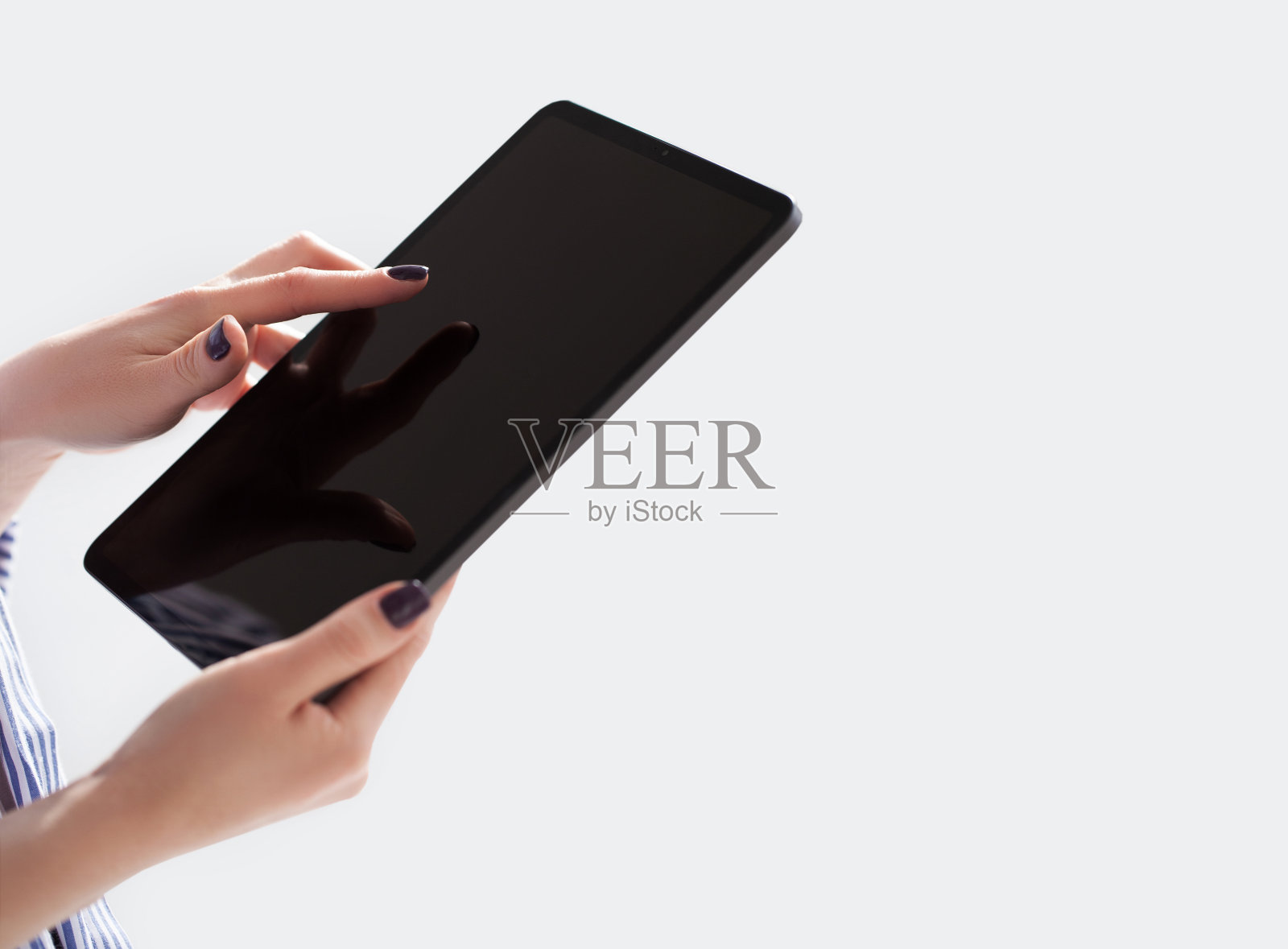 女子手持白底白屏iPad pro。办公室的背景照片摄影图片