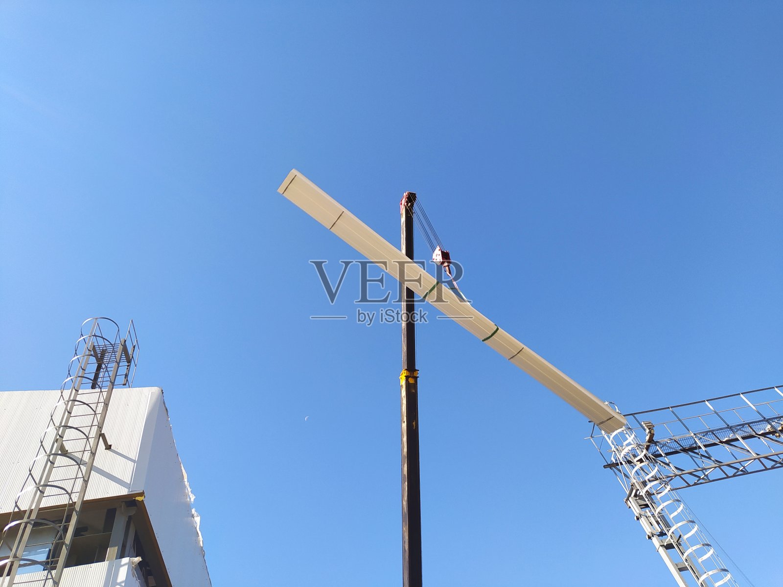 施工现场的施工起重机将荷载吊到建筑物的屋顶上照片摄影图片