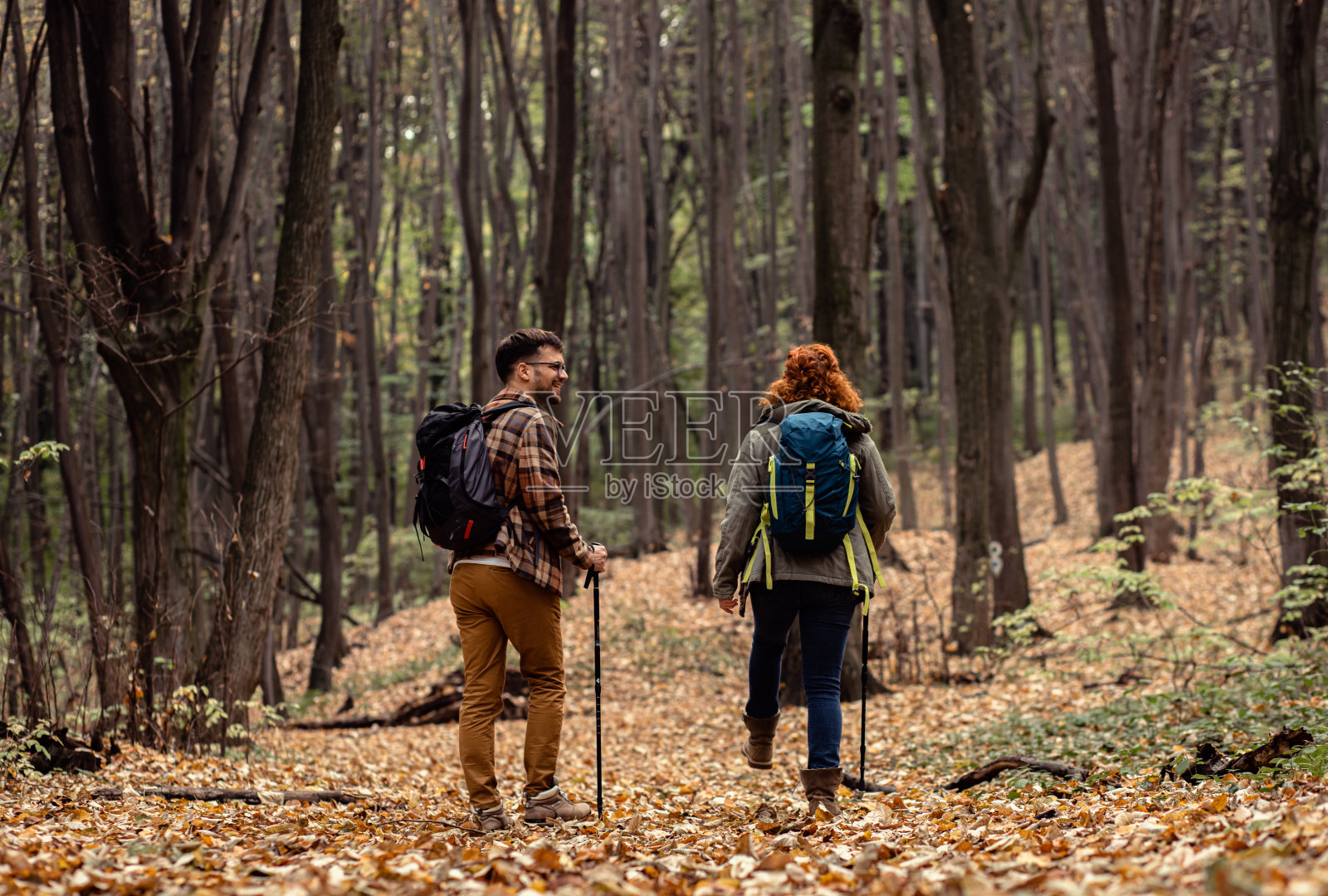 年轻夫妇背着背包在森林里徒步旅行。照片摄影图片