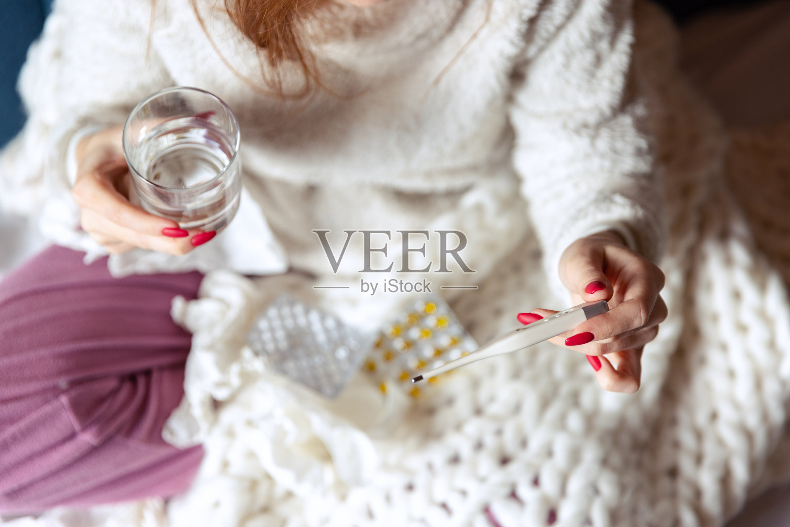 裁剪的俯视图肖像女孩坐在沙发上的毯子和服用药物。流感、感冒,过敏照片摄影图片