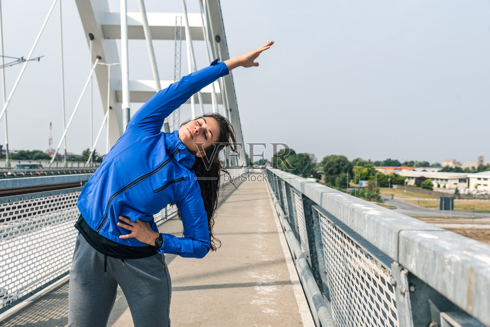 年轻美丽快乐的运动健身女人站在桥上伸展她的肌肉准备慢跑和跑步锻炼，同时她集中精力锻炼和训练动机照片摄影图片