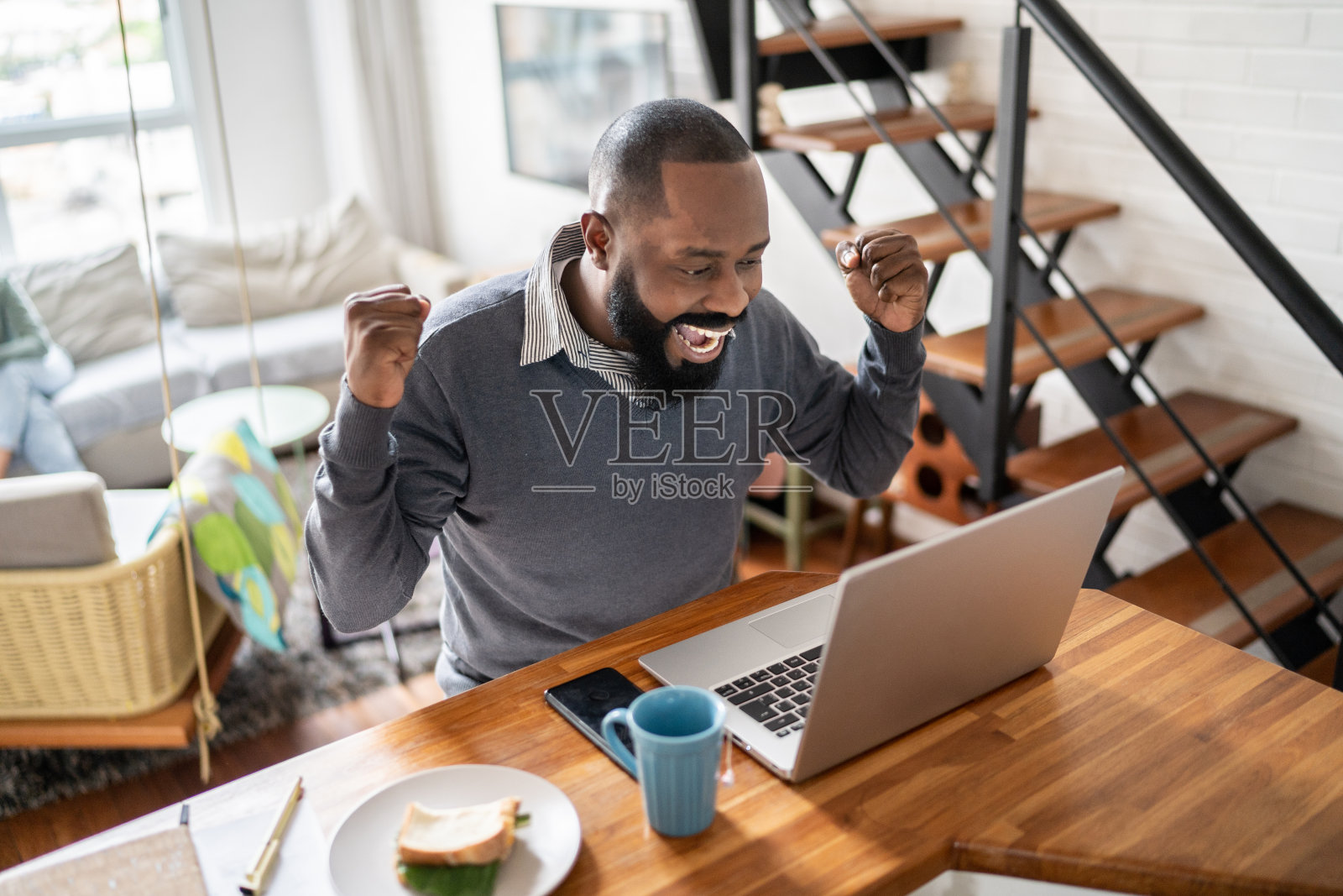 快乐的男人在家里用笔记本电脑庆祝好消息照片摄影图片