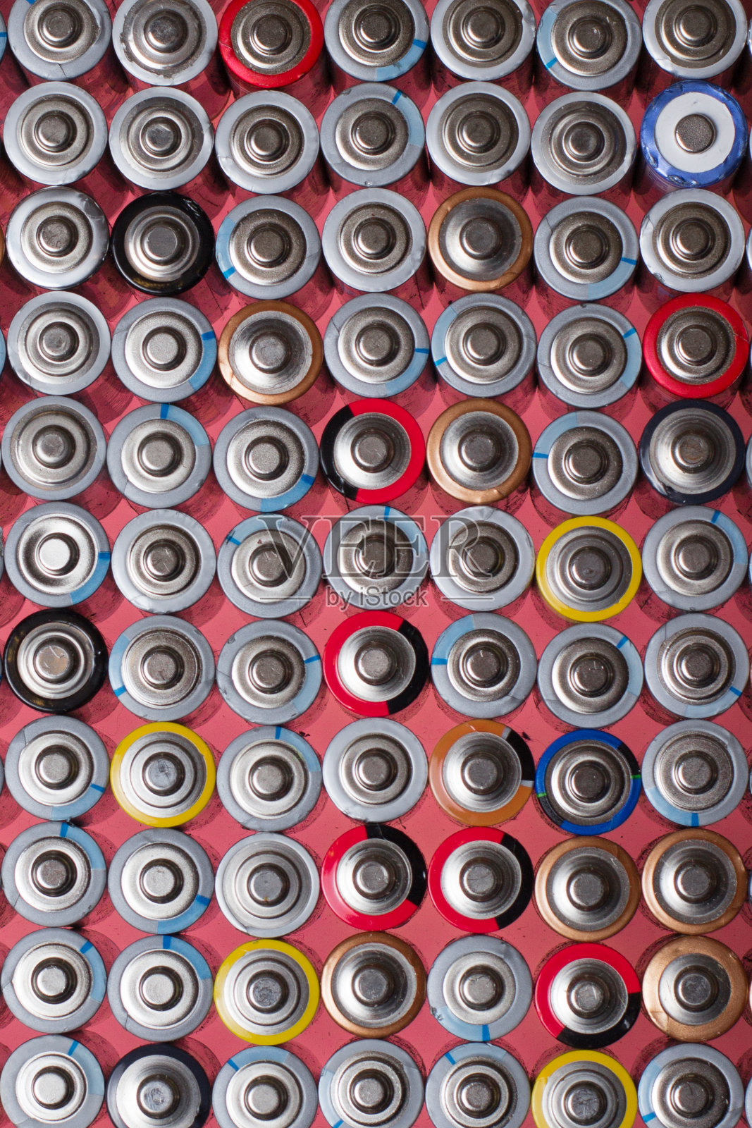 碱性电池在红色的背景上相互叠在一起照片摄影图片