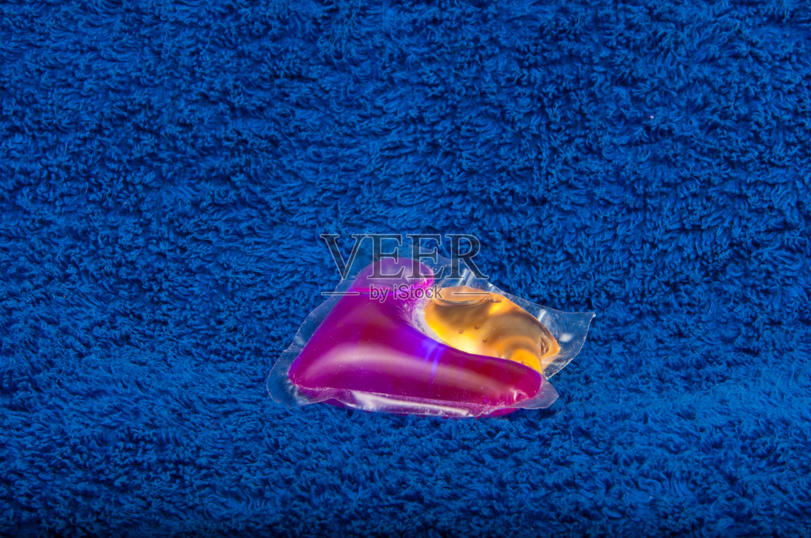 洗色凝胶胶囊在蓝色布的质地上照片摄影图片