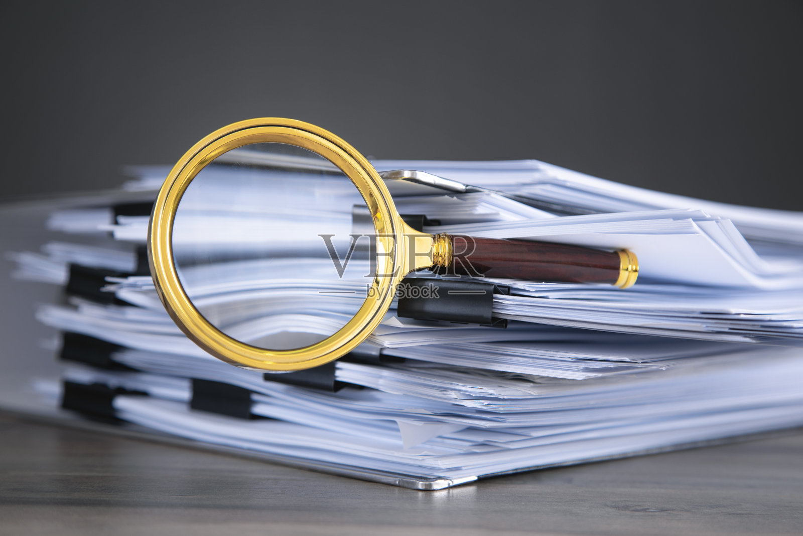桌上堆满了文件和放大镜。照片摄影图片