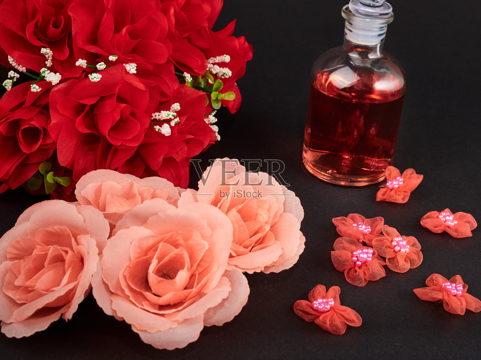 黑色背景上有人工粉红玫瑰的玻璃瓶香水的特写照片摄影图片