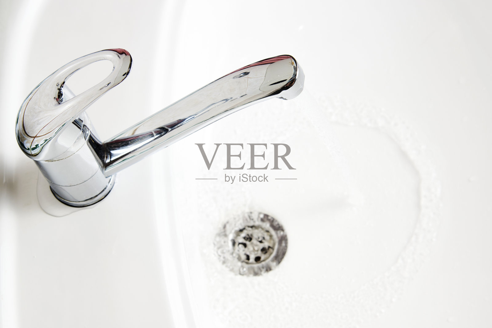 自来水龙头与流动的水进入白色水槽照片摄影图片