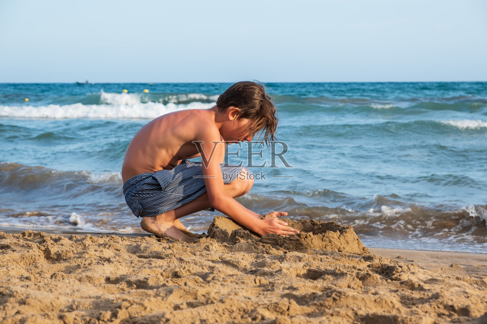 男孩在沙滩上玩沙子照片摄影图片