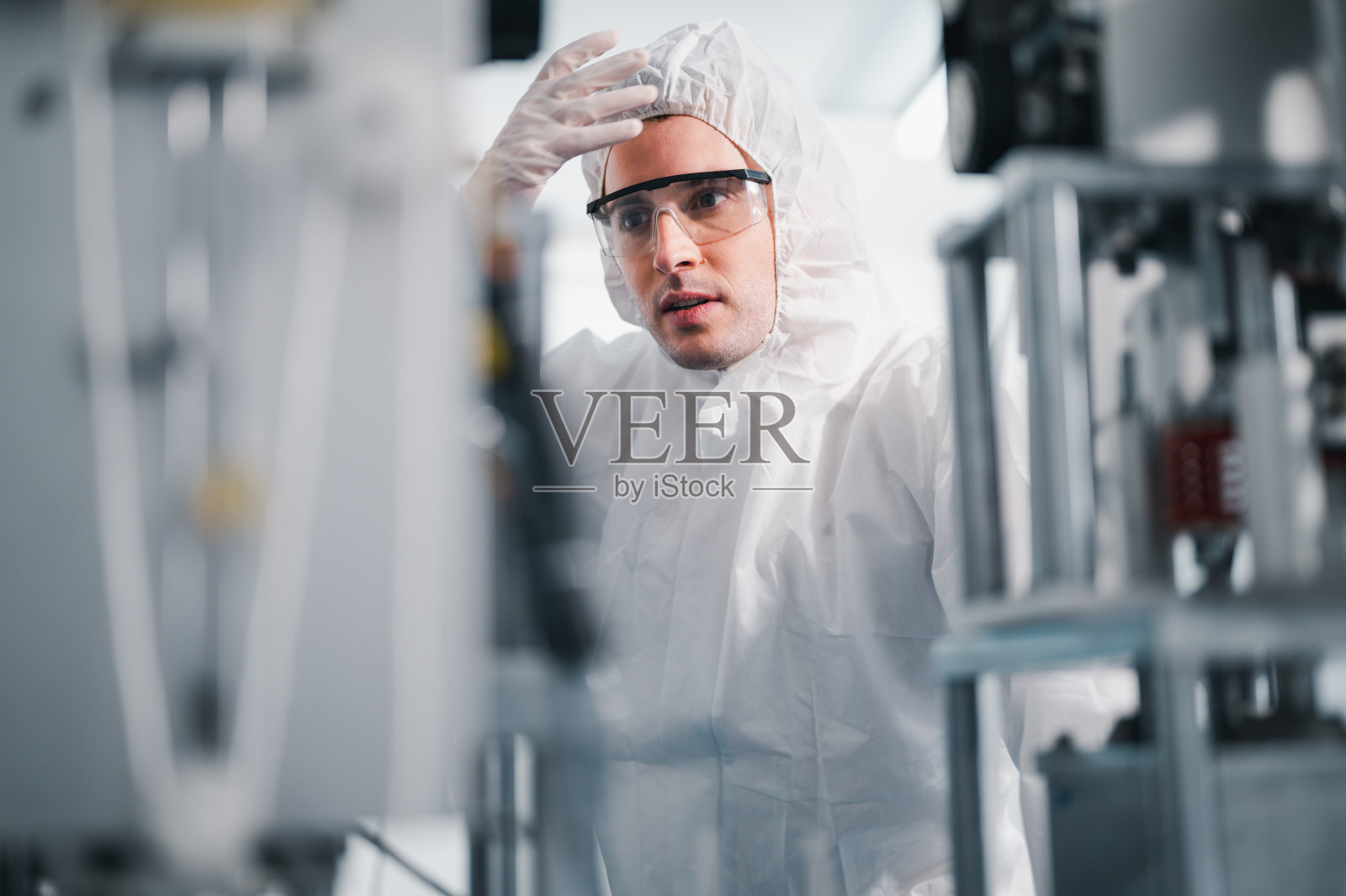 在一个工业工厂的实验室里，科学家们检查面罩制造机器。仓库的杀毒软件。Covid-19是一种冠状病毒。照片摄影图片