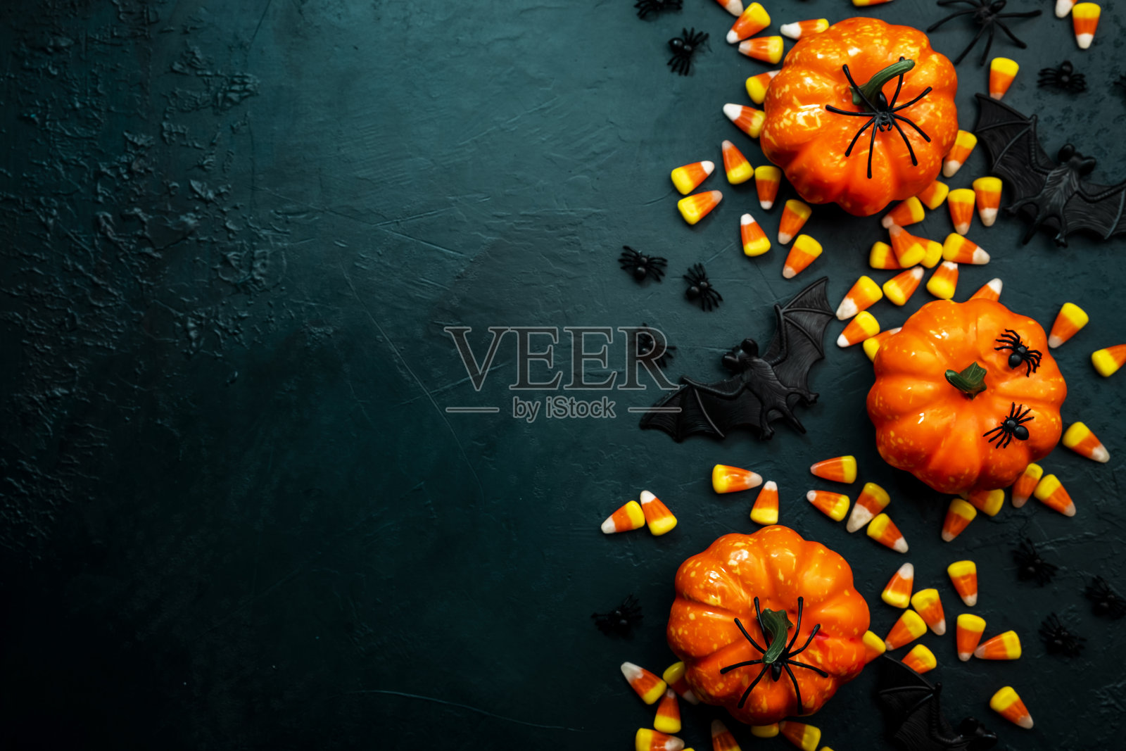 快乐的万圣节蓝色背景与南瓜，蝙蝠，蜘蛛和糖果玉米。带有复制空间的框架边框照片摄影图片