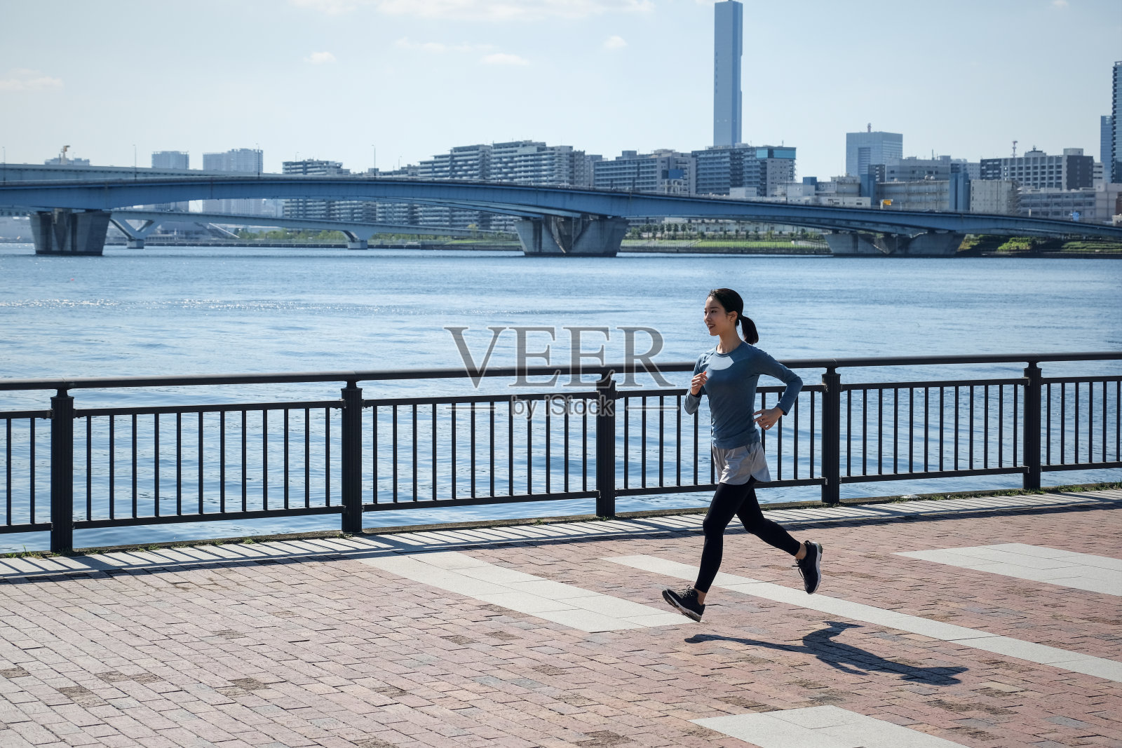 年轻女子在海边的人行道上奔跑照片摄影图片