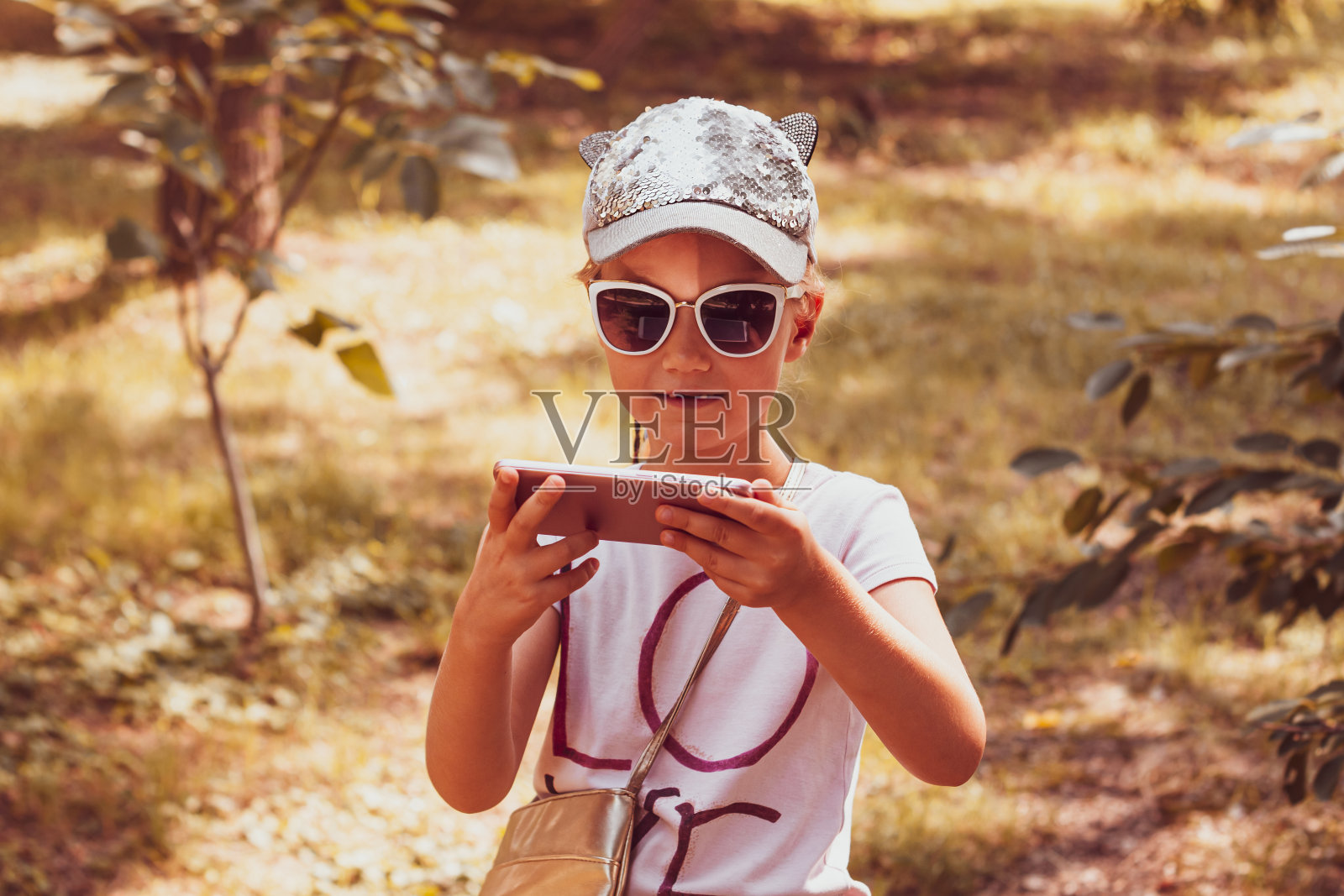 可爱小女孩戴棒球帽户外，扎着长辫。照片摄影图片