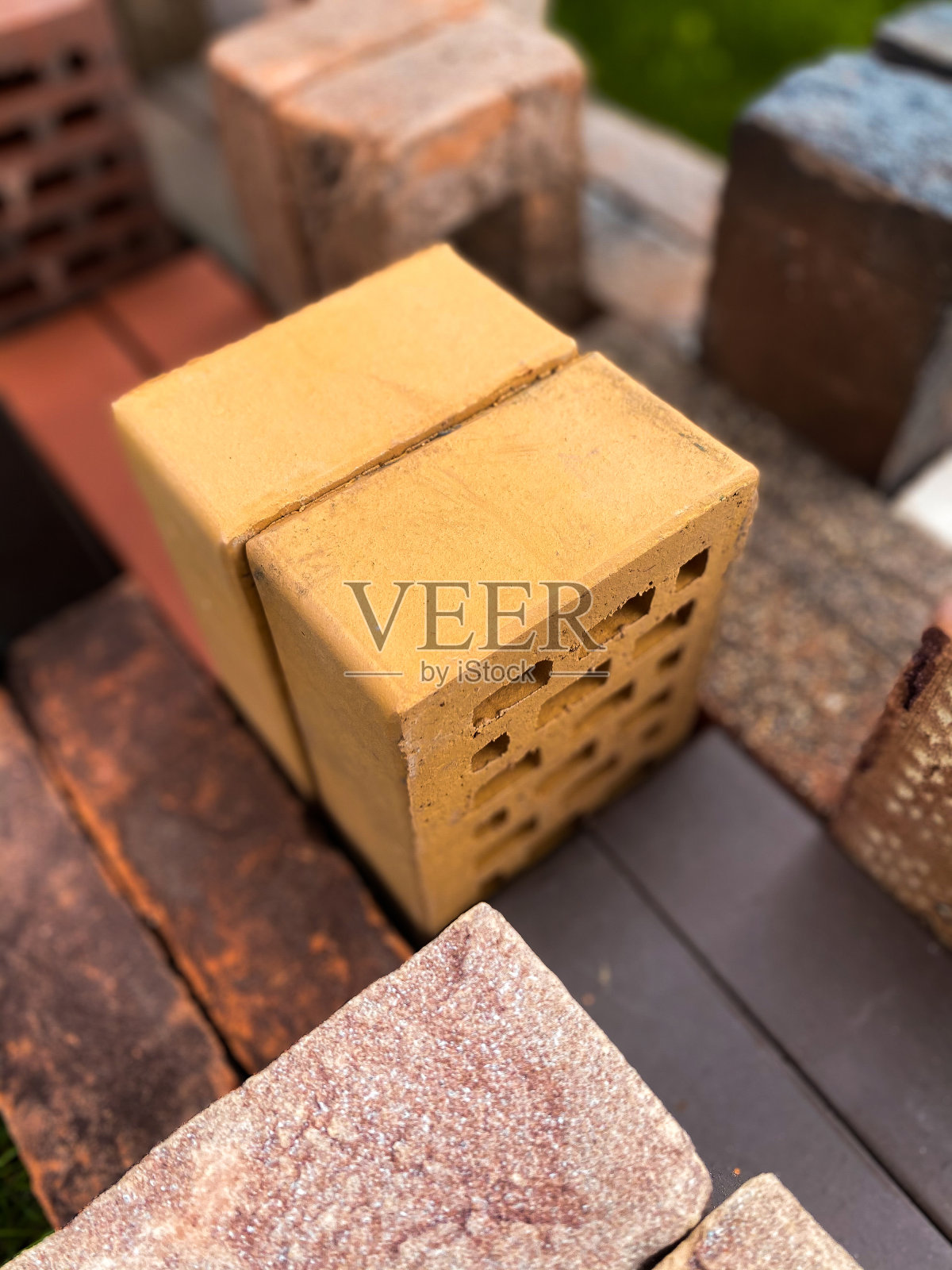 不同类型的砖块漂亮地堆放在绿色的草地上照片摄影图片