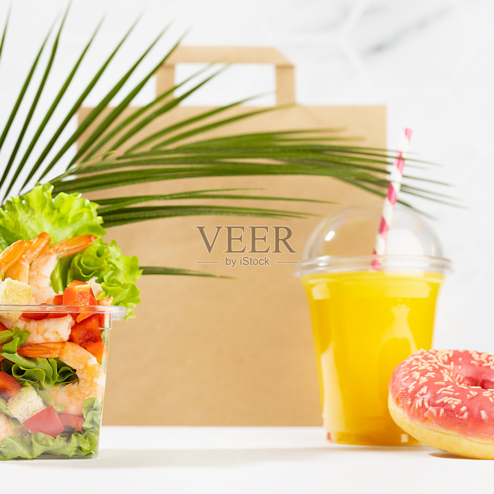 夏季午餐套装海鲜虾仁沙拉包，橙汁，甜甜圈，包在白色的内部大理石瓷砖，棕榈叶，正方形。为外卖服务，外卖餐厅的广告模型。照片摄影图片