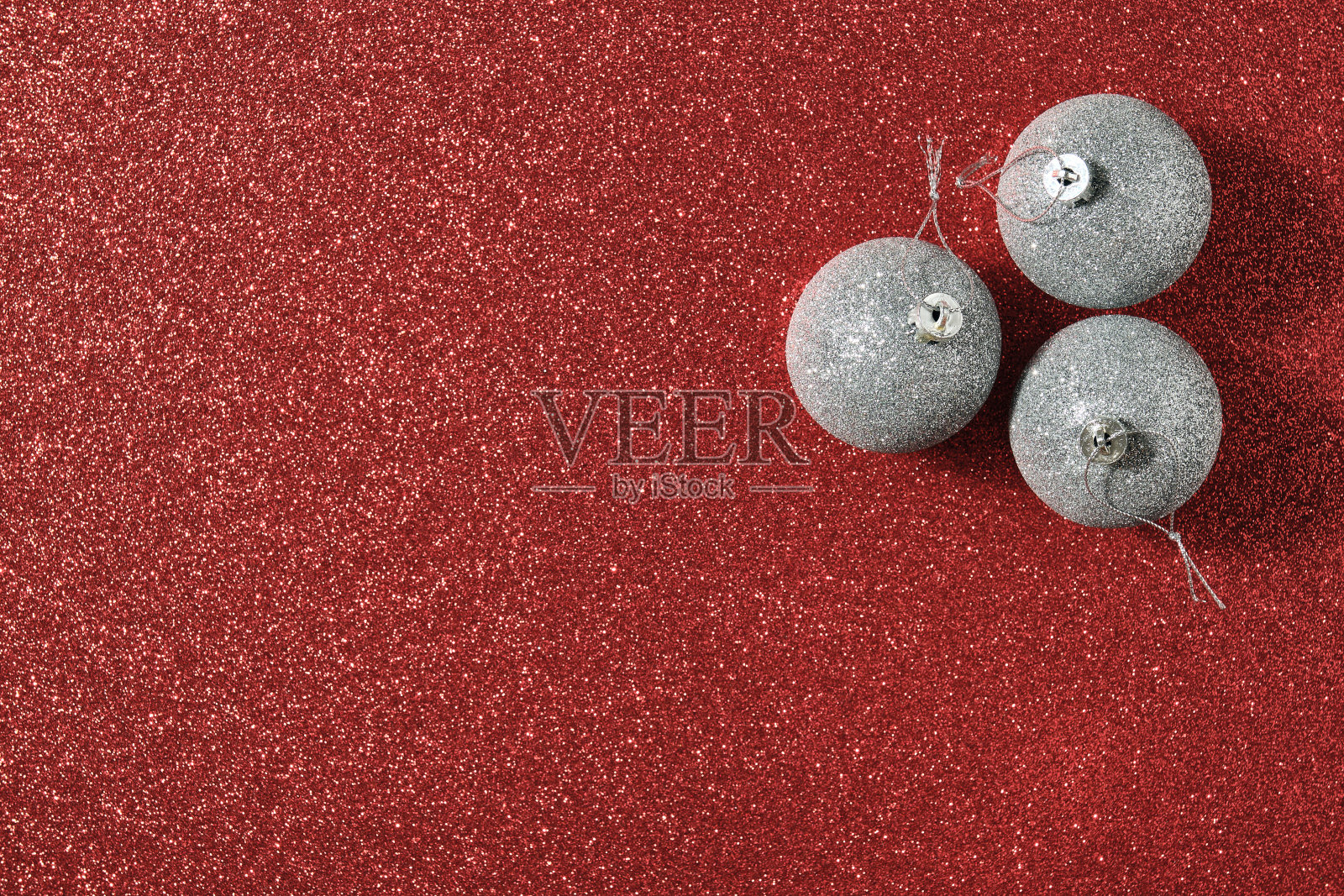 图片右下角有三个银质的圣诞球，背景是亮红色的金色照片摄影图片