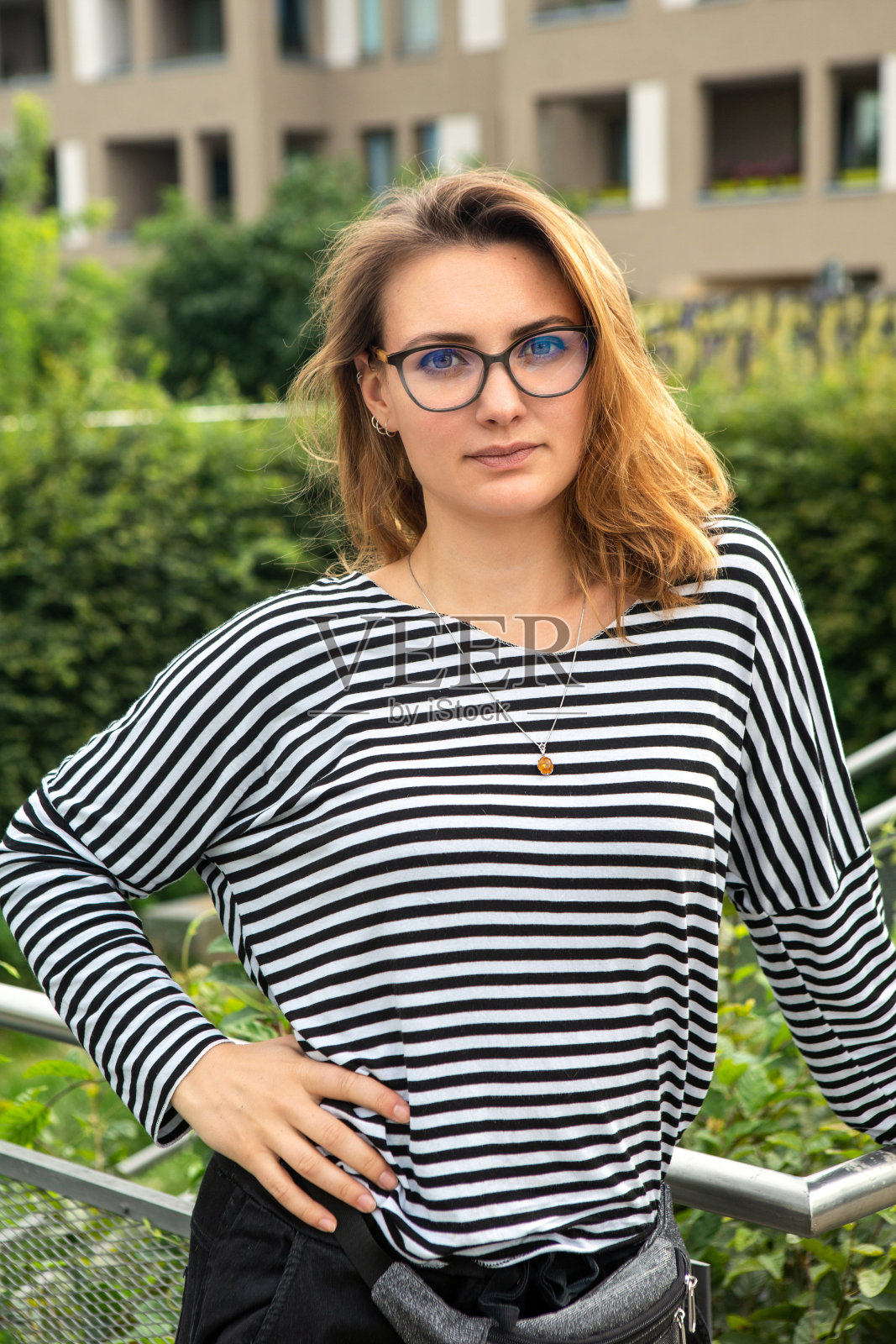 的画像。一个戴着眼镜的黑发年轻女人站在公园里照片摄影图片