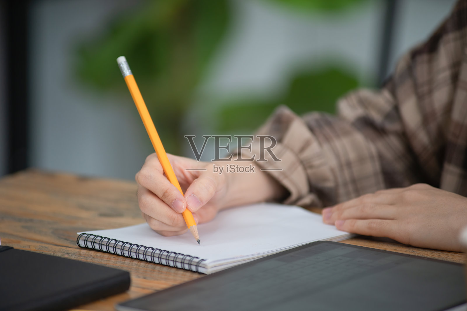 女人们用铅笔在笔记本上写字。照片摄影图片