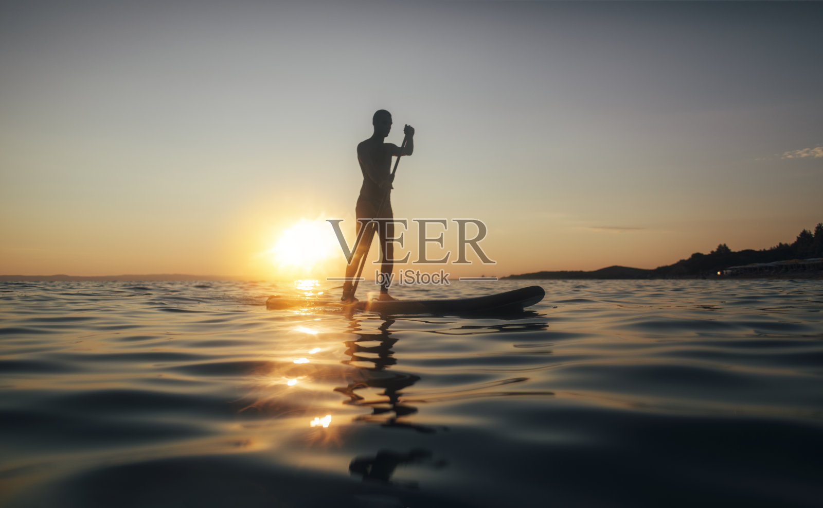 一个男人在日落的海面上划桨的剪影照片摄影图片