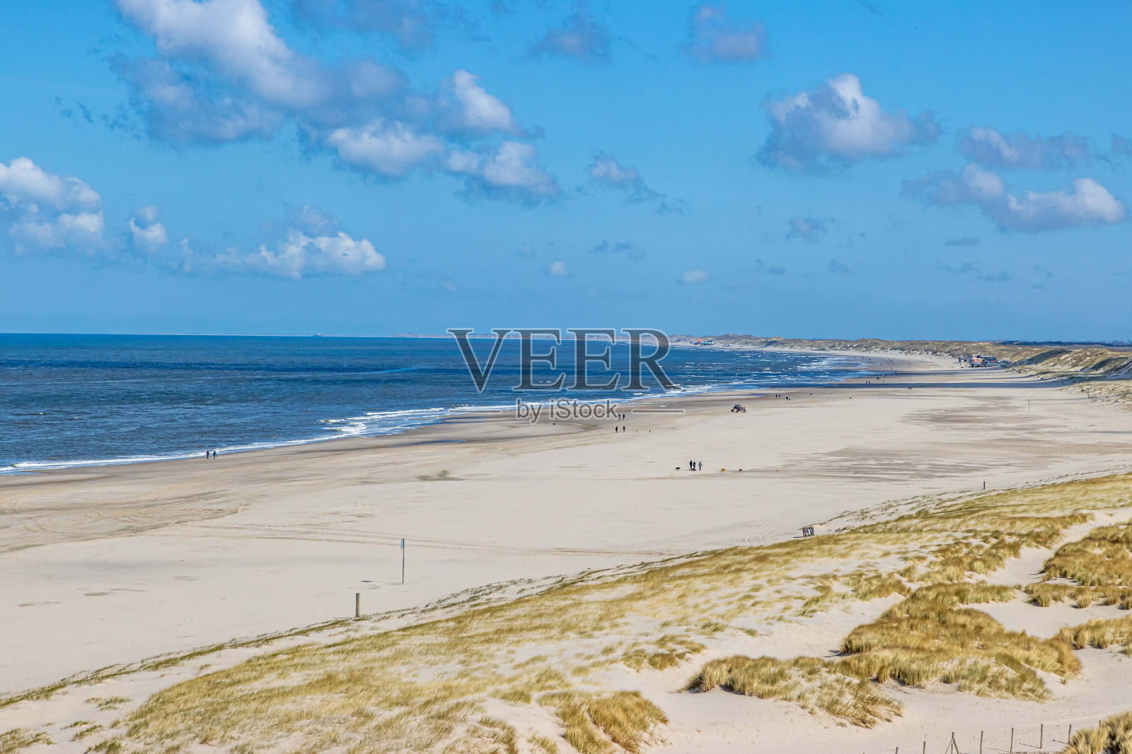 远处棕色的沙滩上，人们在散步，玛拉姆草，大海和地平线在后面照片摄影图片