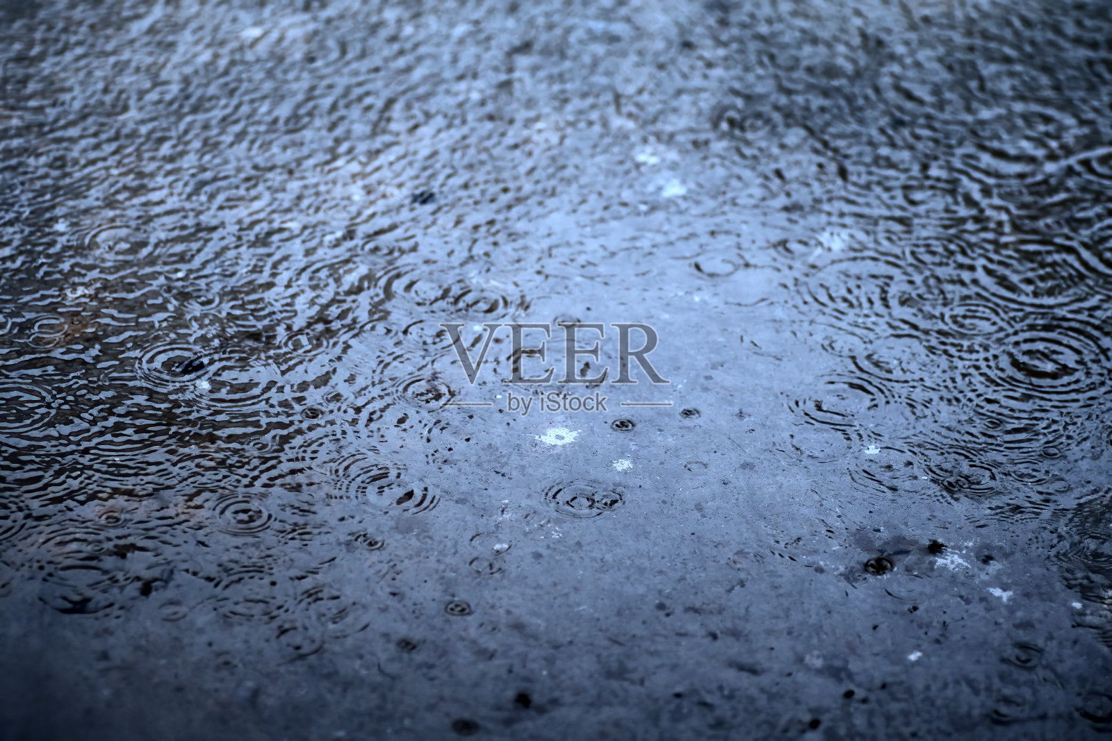 在雨天，雨滴落在地上时溅起的小花冠，背后是蓝色的色调和金色的阳光照片摄影图片