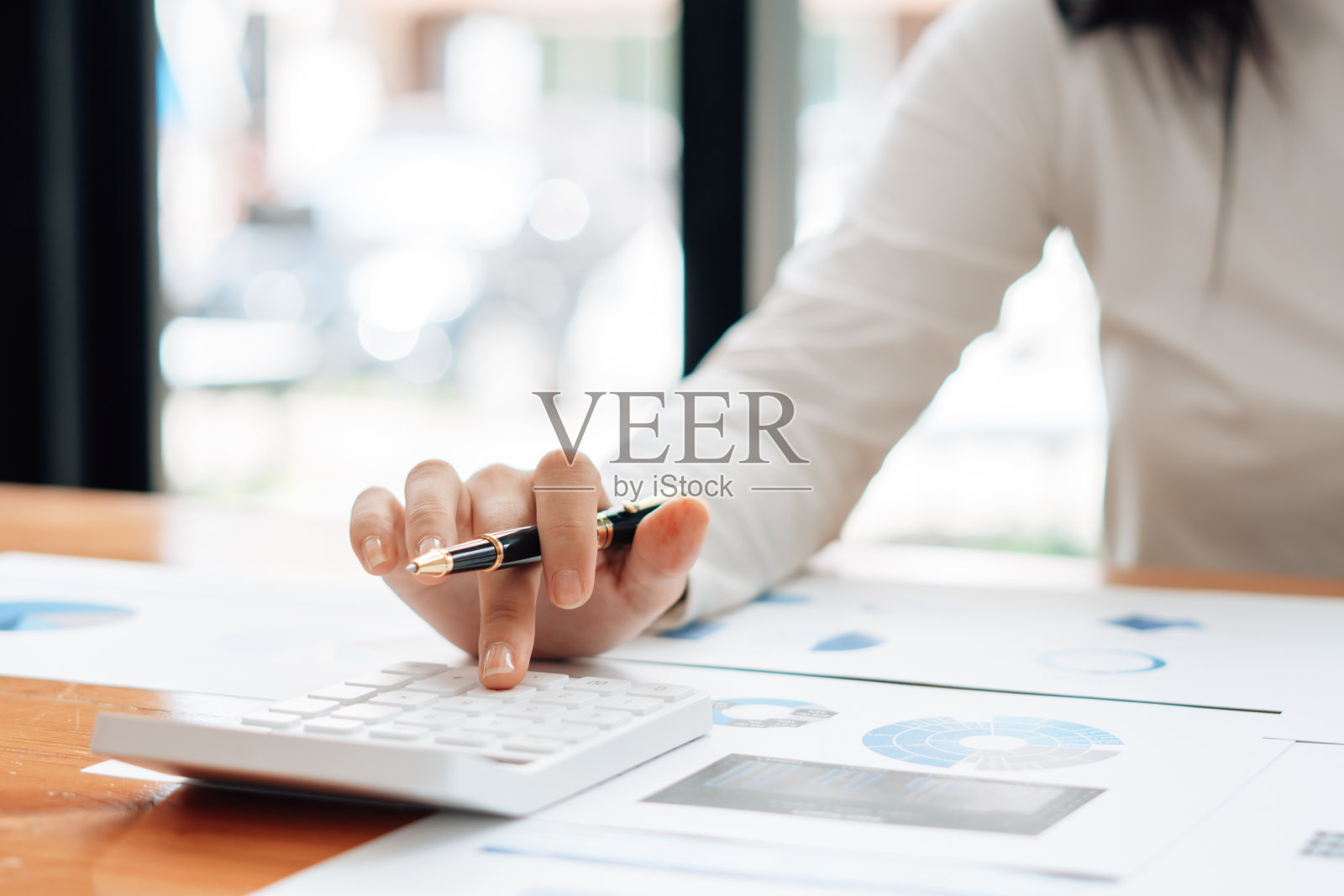 在办公室，商人或会计手握笔在计算机上计算业务数据、会计文件和笔记本电脑上工作，经营理念。照片摄影图片