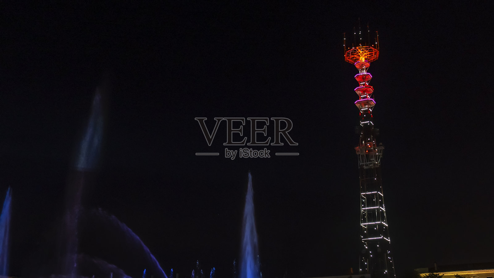 电视塔在节日的灯光下。在前景喷泉与长曝光水滴。节日的概念。照片摄影图片