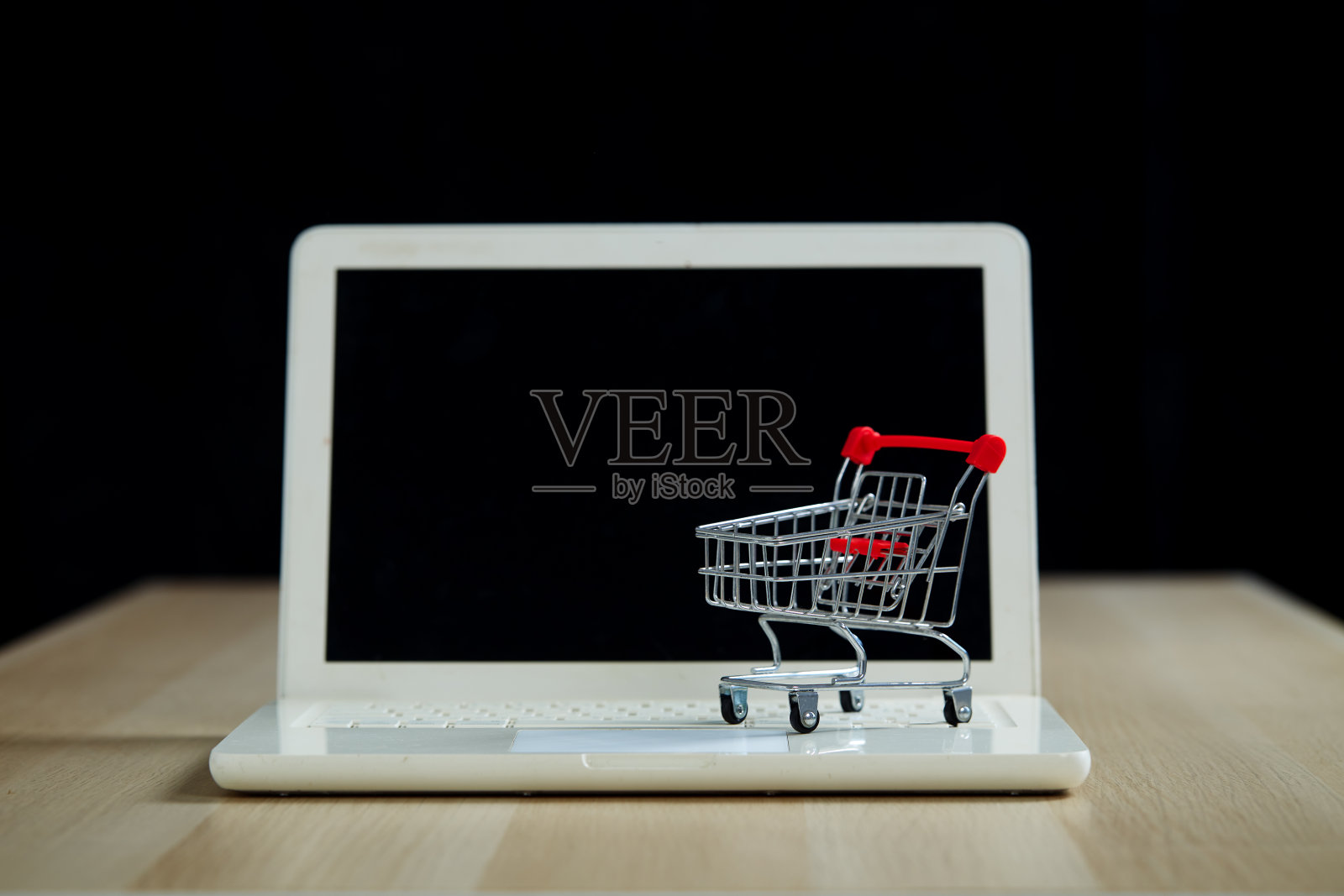 黑色星期五购物和零售概念。黑色背景木桌上的购物车笔记本电脑照片摄影图片