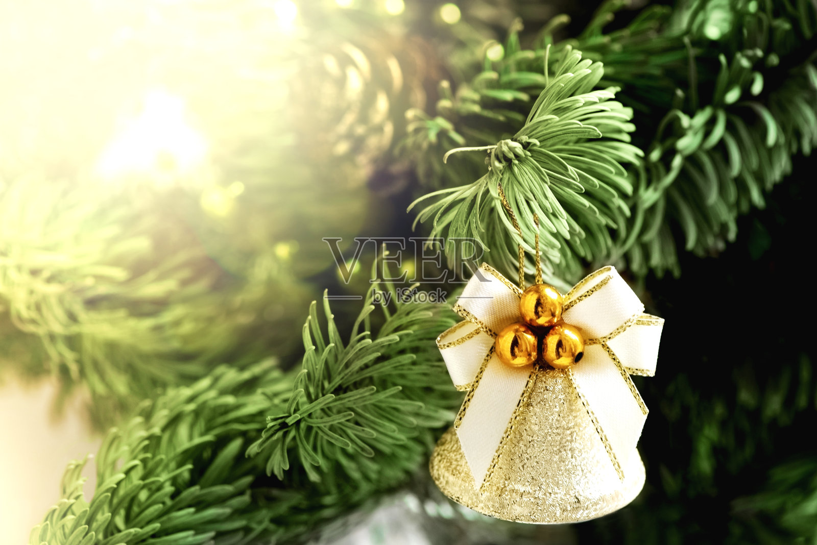 圣诞树树枝上的圣诞铃铛，背景上模糊的花环灯照片摄影图片