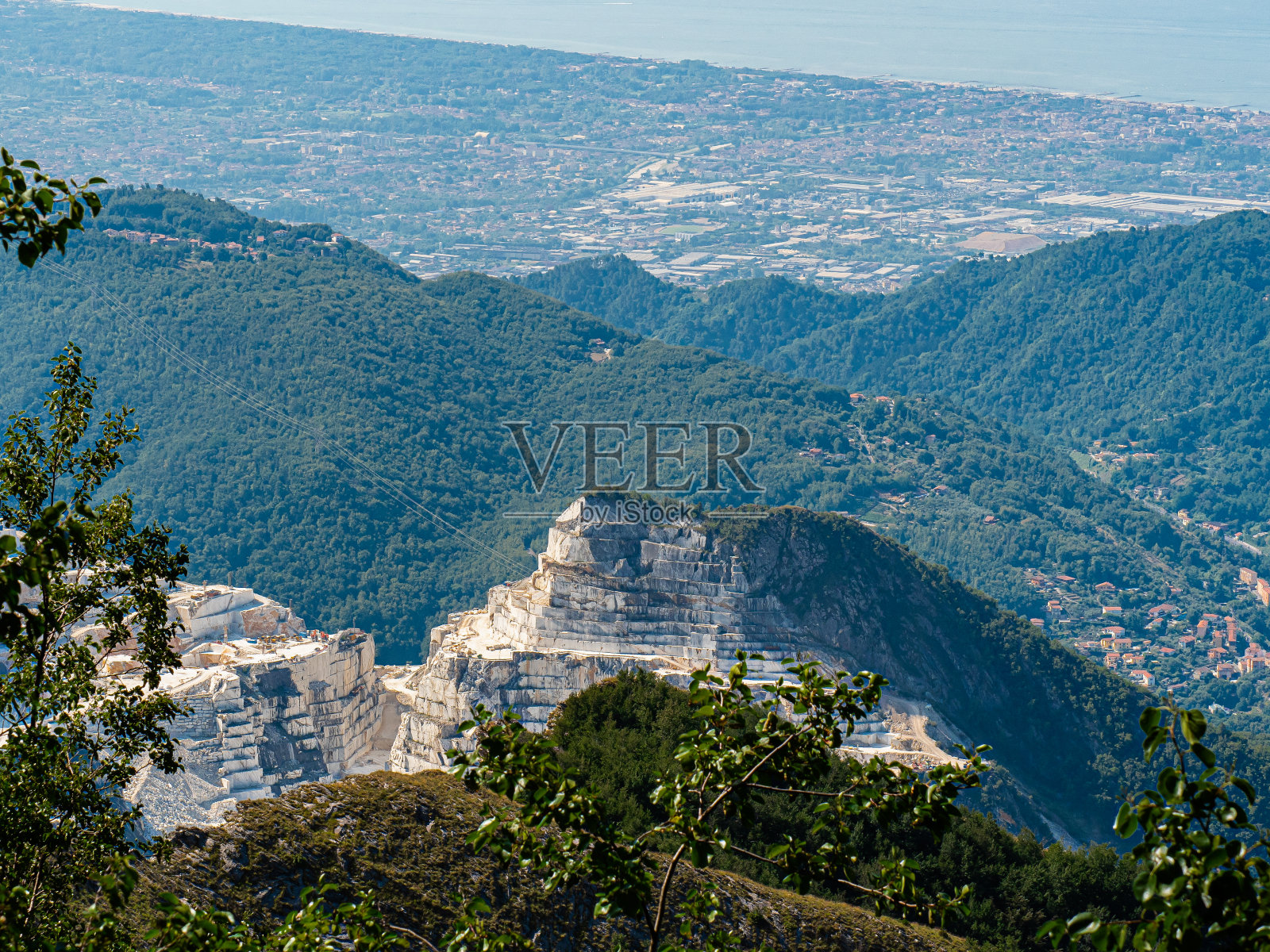 欣赏卡拉拉的大理石采石场，山坡上的小径，以及前面的卡拉拉镇和海岸照片摄影图片