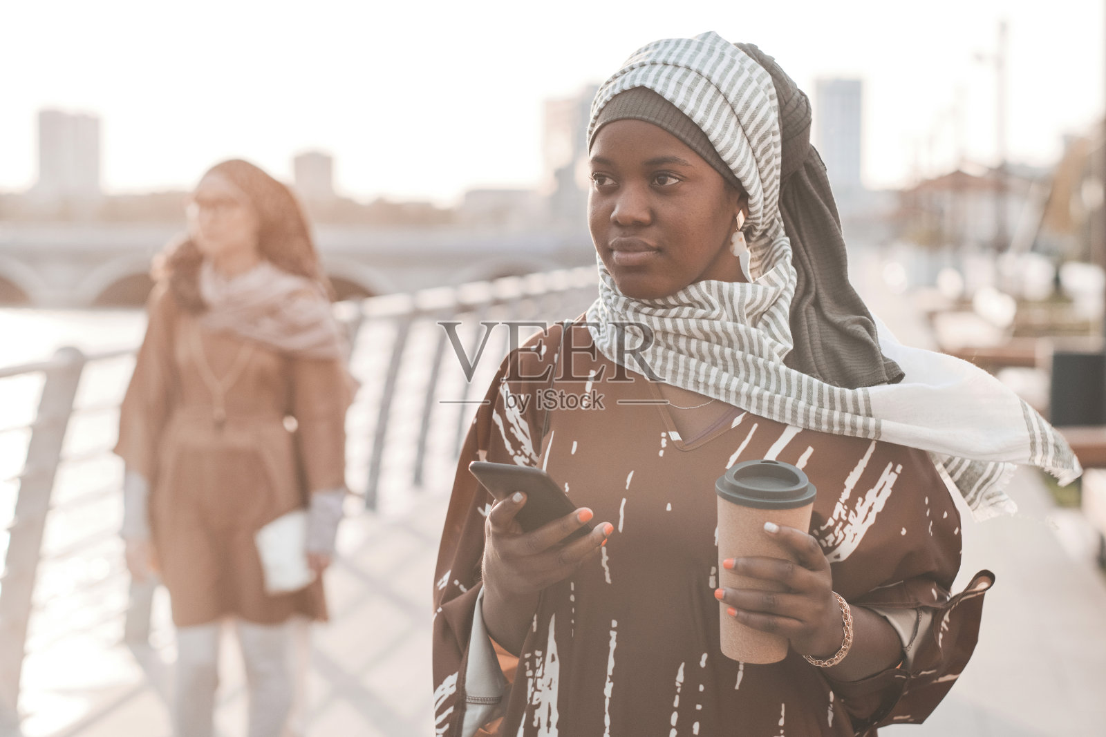 在城市中行走的喝咖啡女人照片摄影图片