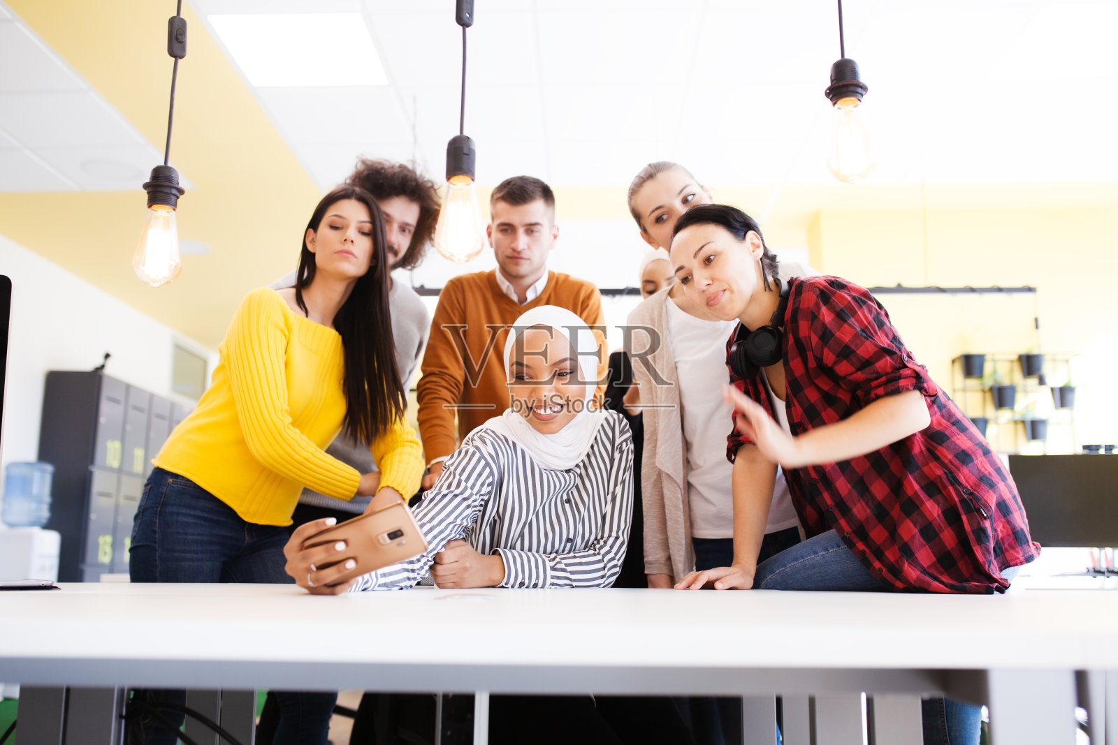 一群成功的多种族同事在现代办公场所自拍。所有人都开心地微笑着，对着镜头挥手。照片摄影图片