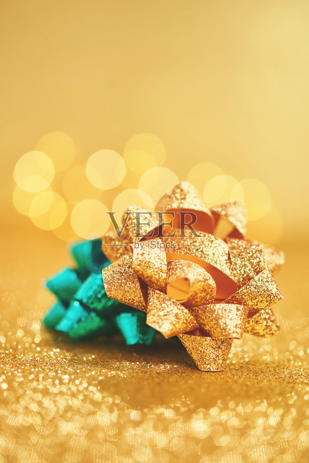 金色和蓝绿色的弓在闪闪发光的金色背景照片摄影图片