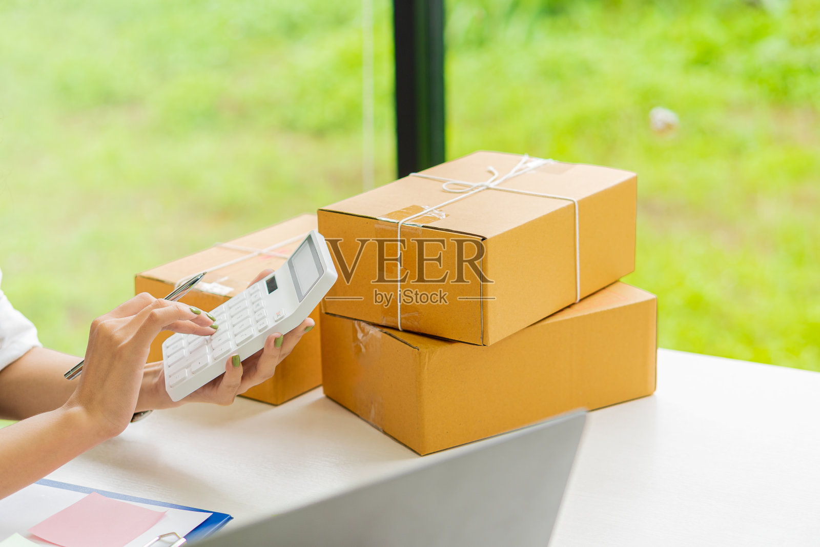 亚洲自由职业女孩中小企业网上购物工作在笔记本电脑，从客户的订单与包裹箱在家庭办公桌-中小企业网上业务的想法和送货。照片摄影图片