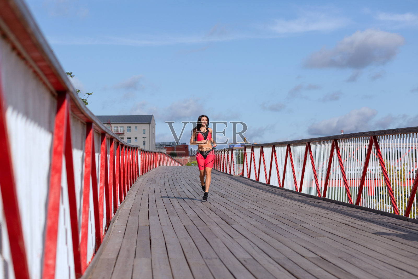 一个穿着粉红色运动服的女人从桥上跑过照片摄影图片