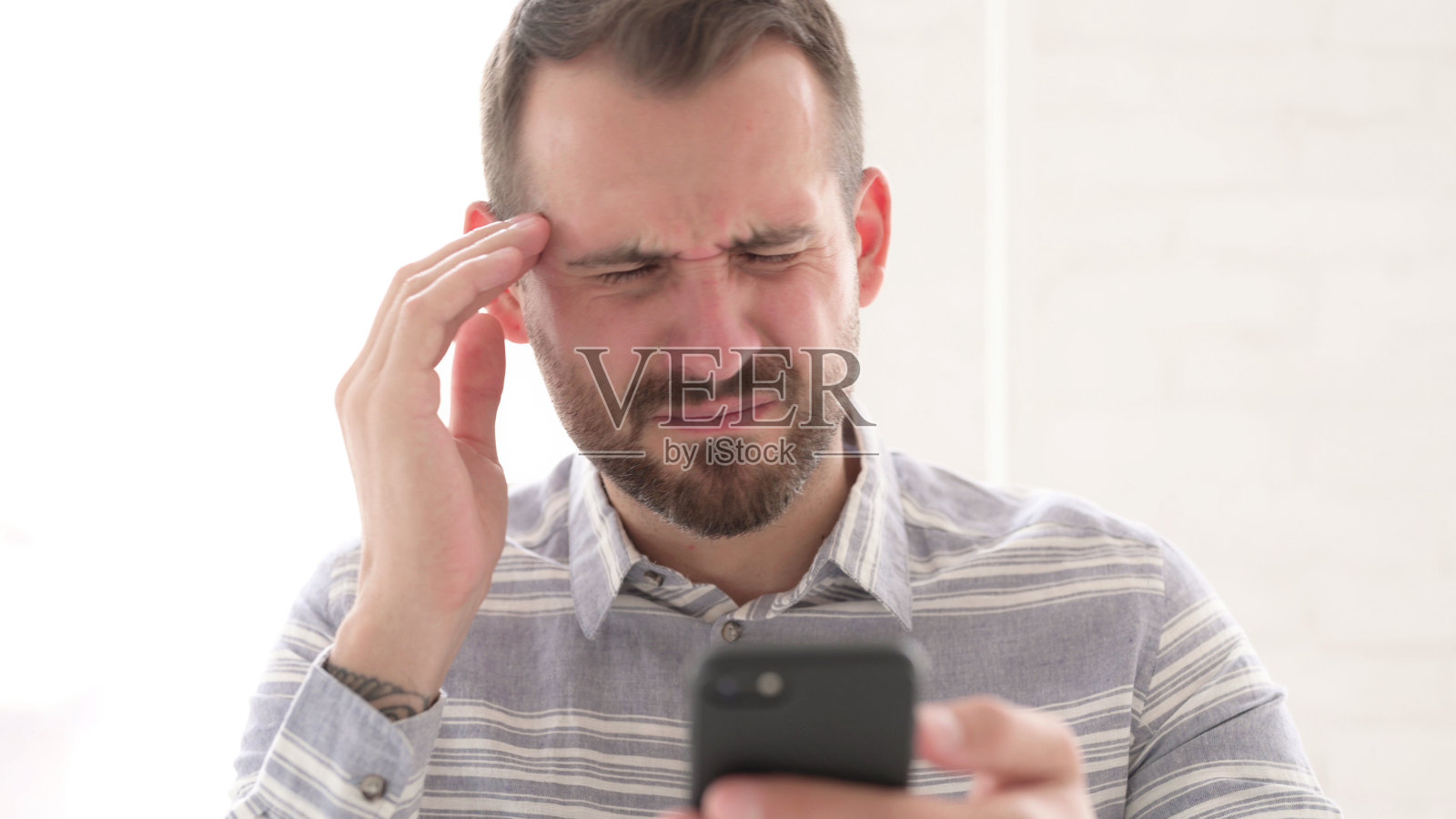 头痛男子使用智能手机的特写镜头照片摄影图片