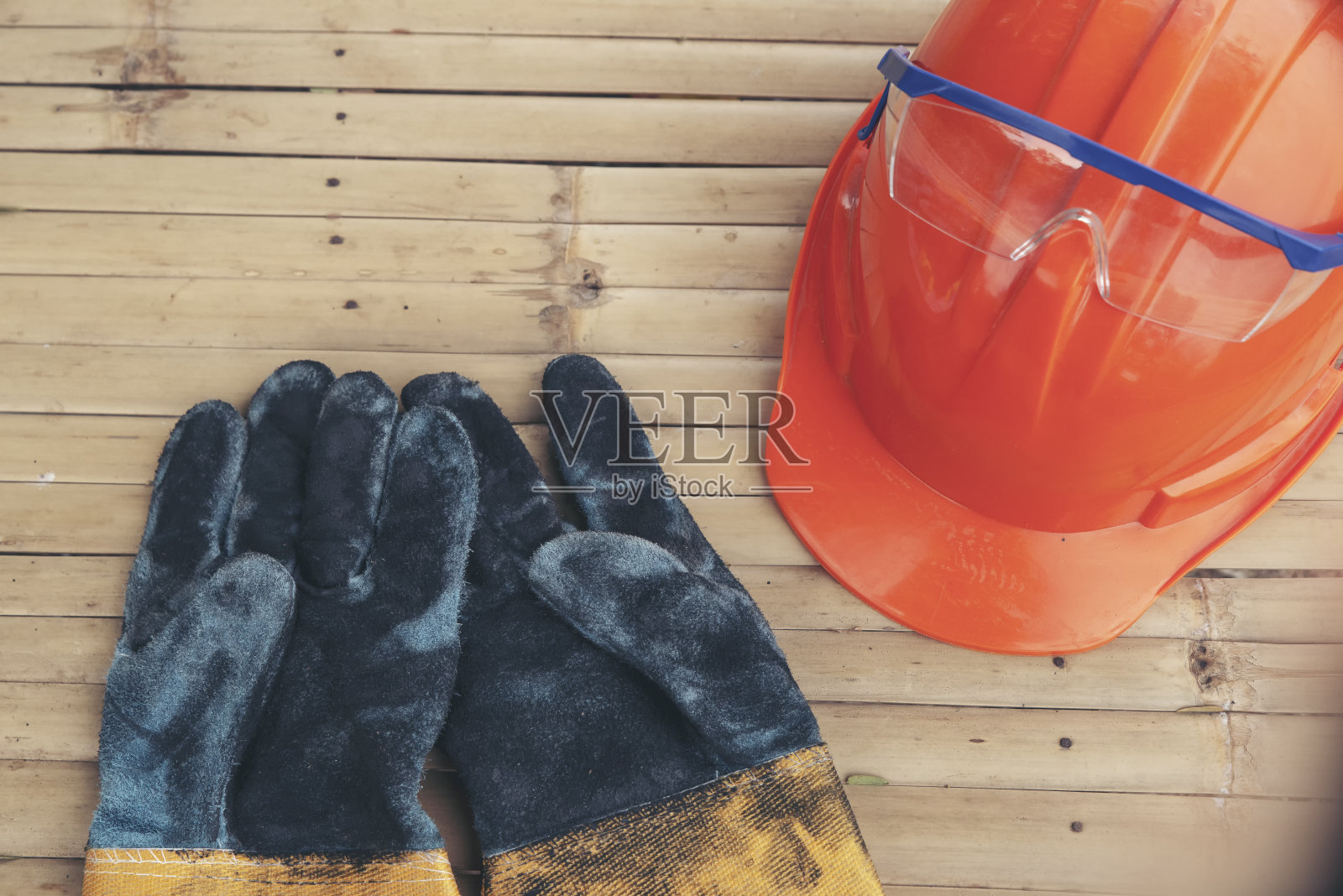 工程师、安全员或建筑师的安全帽(安全帽)和手套的俯视图，放在旧木地板上。施工现场橙色安全帽(安全帽)。照片摄影图片