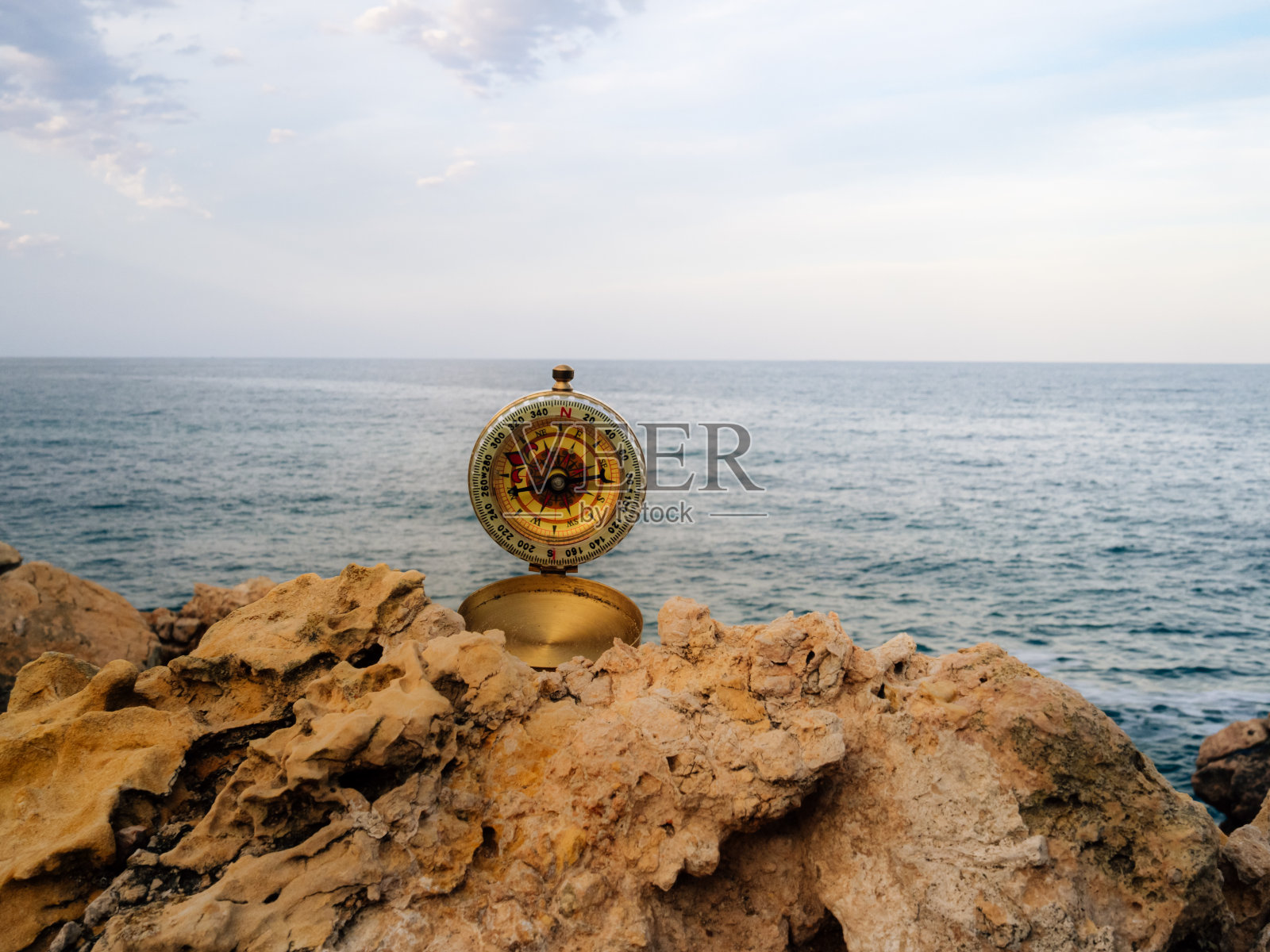 罗盘在岩石上，海面在地平线上。冒险的概念照片摄影图片
