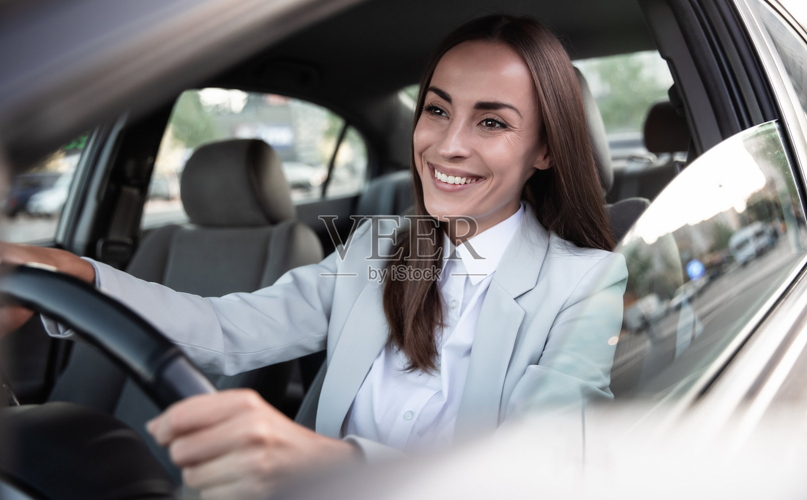 美丽、快乐、成功的女商人正心情愉快地驾驶着一辆新式汽车。肖像可爱女司机驾驶汽车与安全带照片摄影图片
