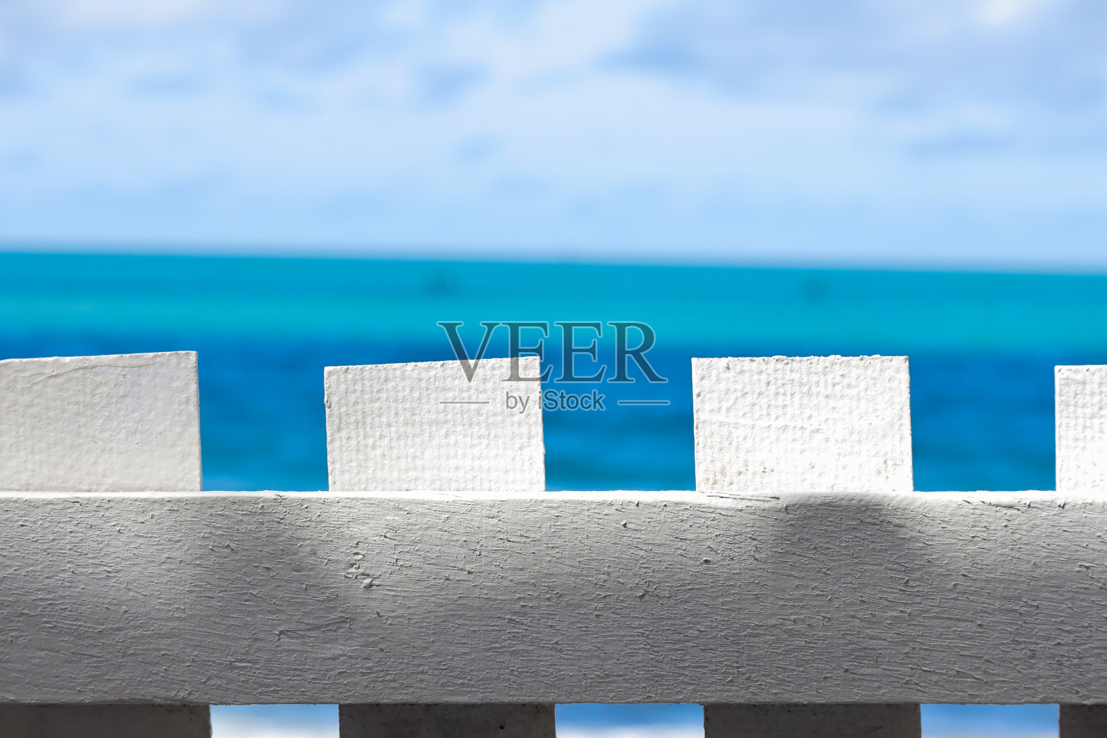 大海背景上的白色木栅栏。照片摄影图片