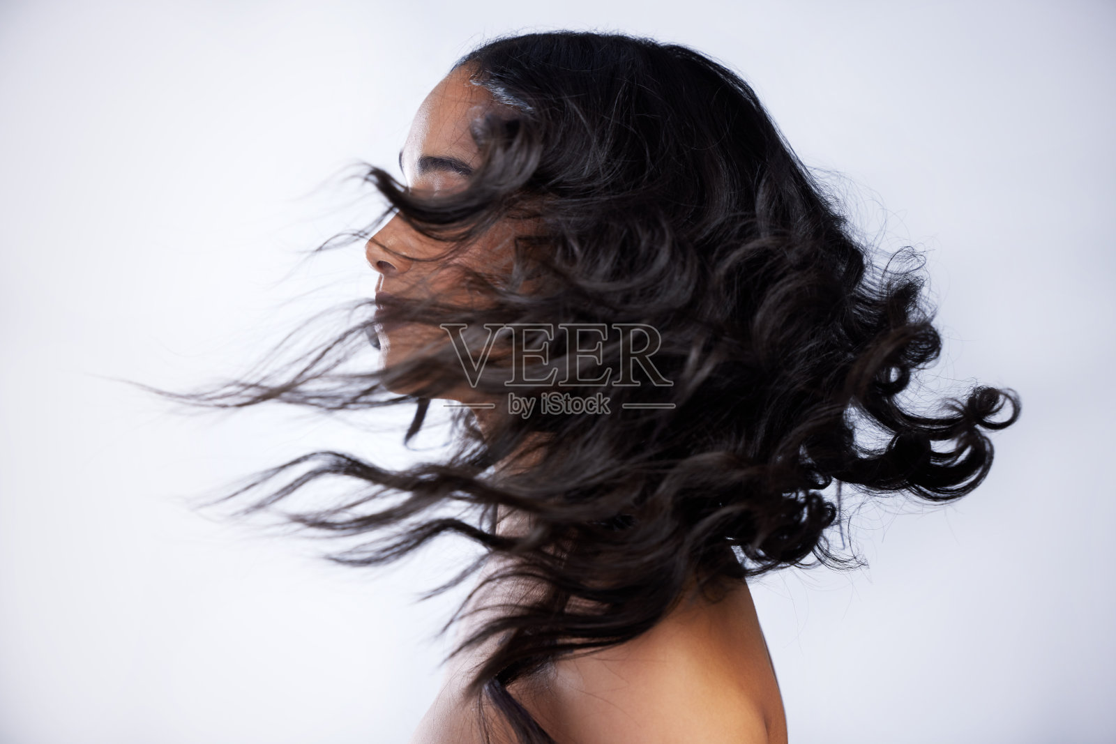 一个不知名的女人独自站在摄影棚，拨弄着她的头发照片摄影图片