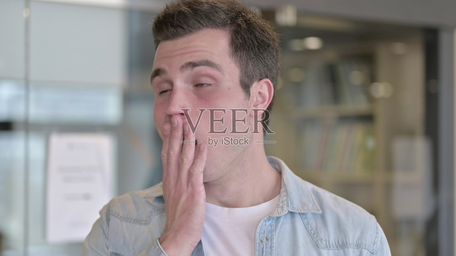 困倦的年轻男性设计师在办公室打哈欠的肖像照片摄影图片