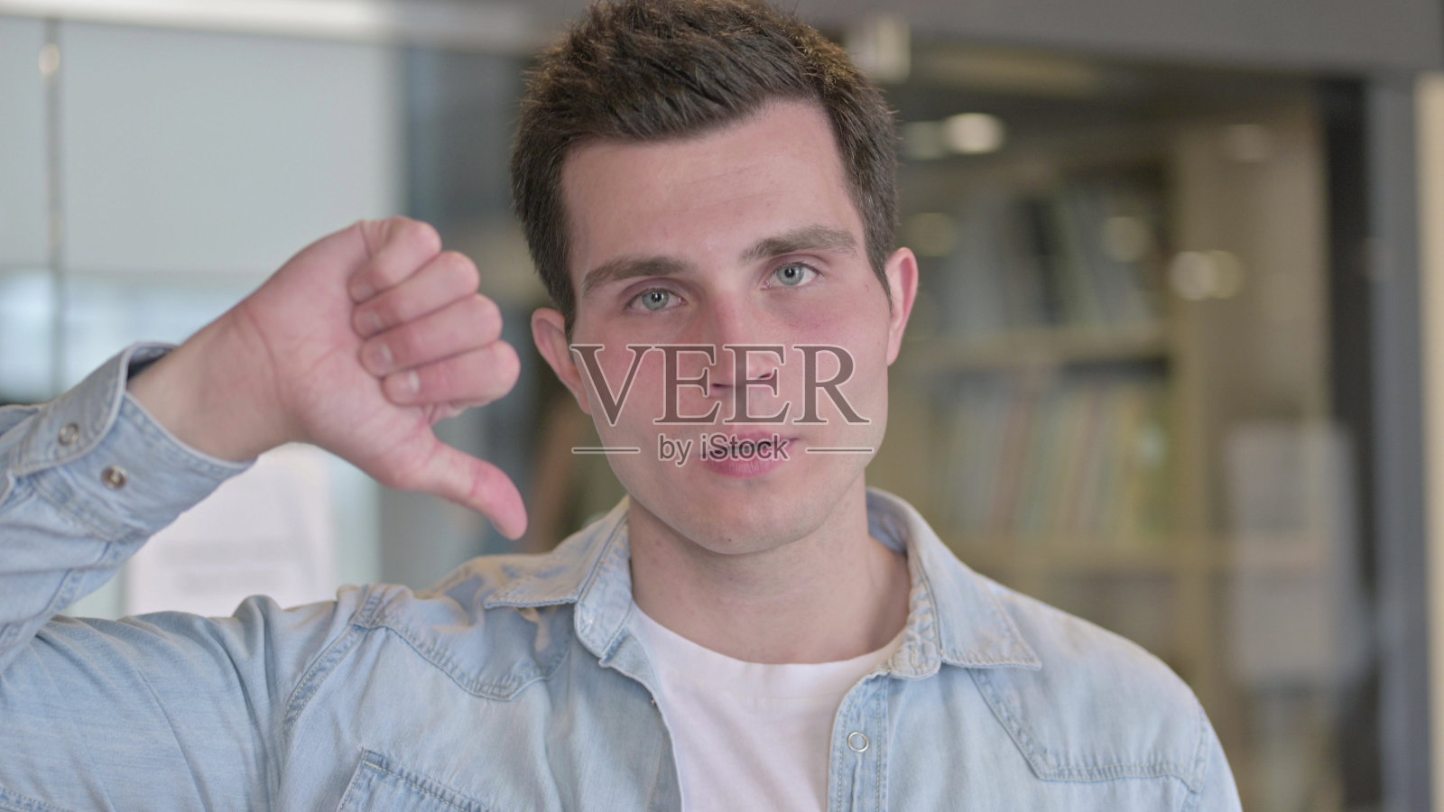 不开心的年轻设计师的肖像显示拇指向下照片摄影图片